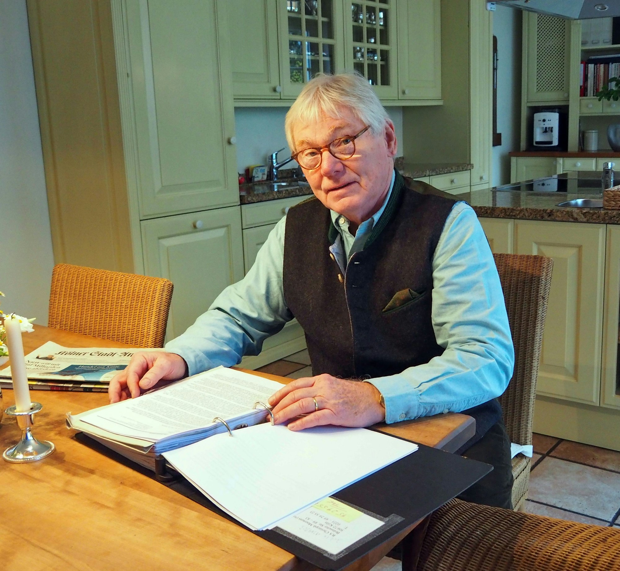 Christian Genzow sitzt an seinem Esstisch mit einem Order voller Schreiben vor sich.