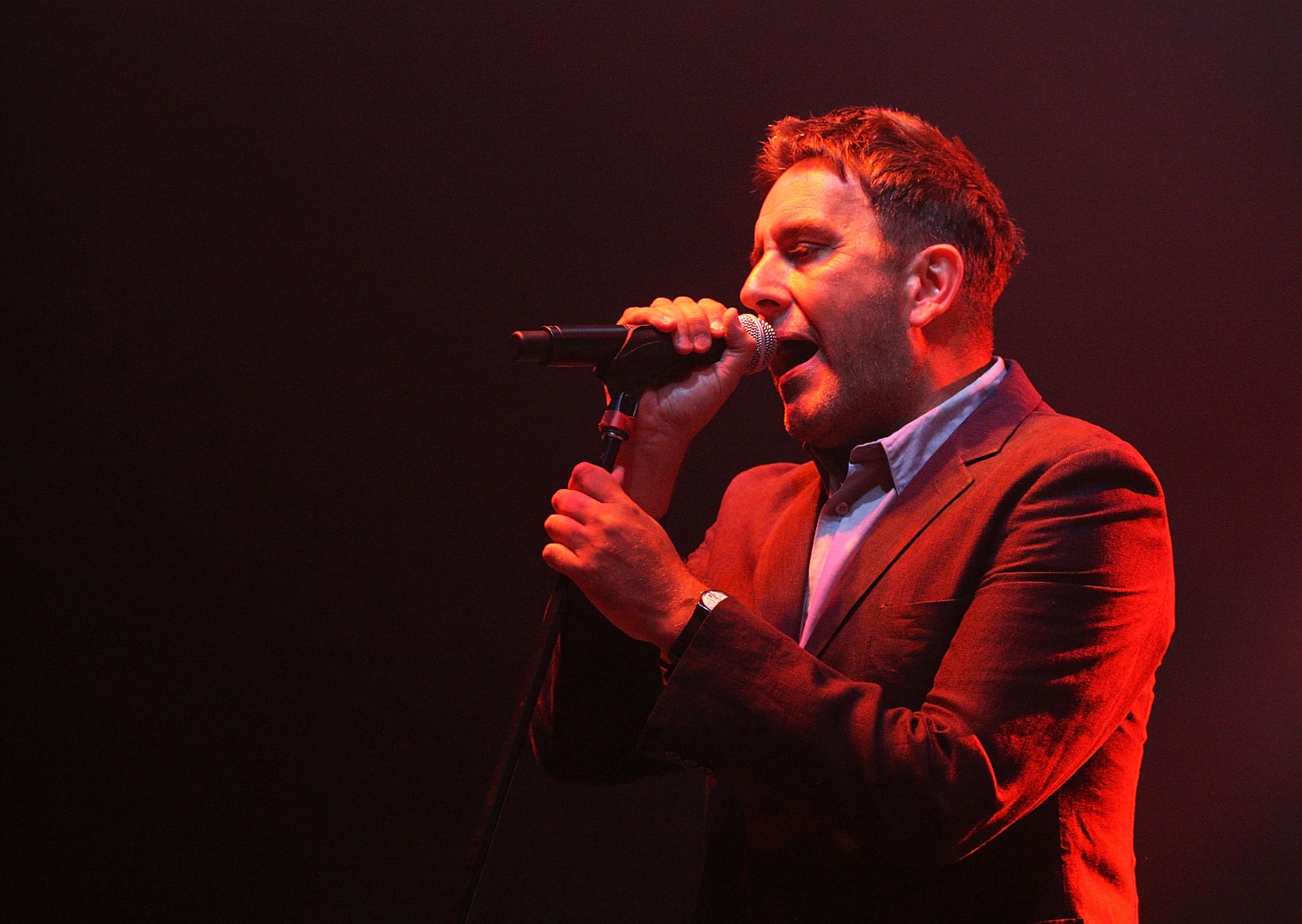 Terry Hall bei einem Auftritt. Er hält ein Mikrofon in der Hand.