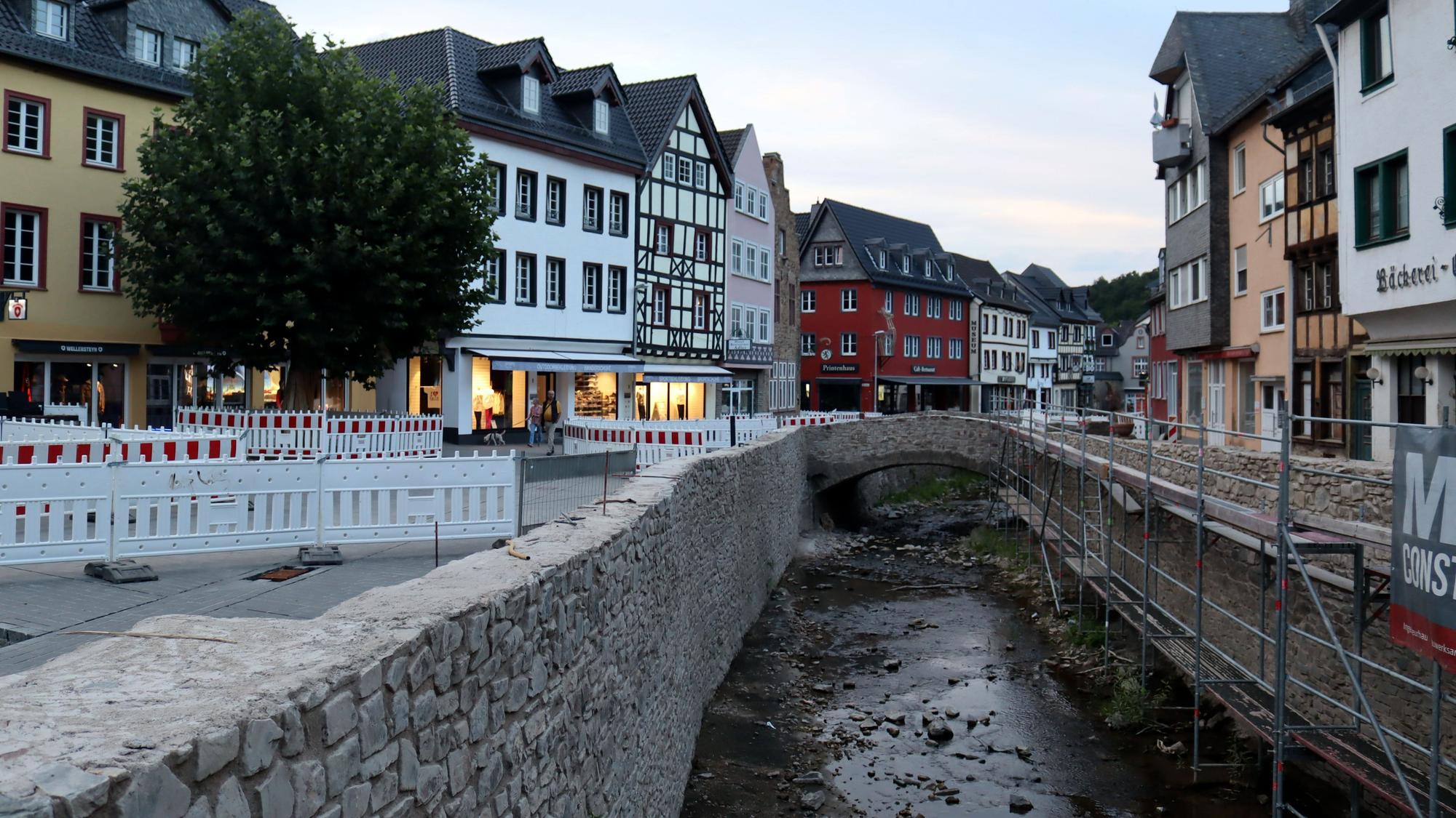 Die Stadt Bad Münstereifel bei einer Aufnahme in den Abendstunden im August 2022. Die Erft ist noch voller Steine, die Mauern noch nicht komplett wiederhergestellt, der Markt ist abgesperrt wegen Wiederaufbauarbeiten.