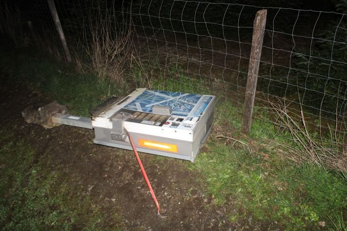 Ein Zigarettenautomat liegt aus der Verankerung gerissen auf einem Wirtschaftsweg.