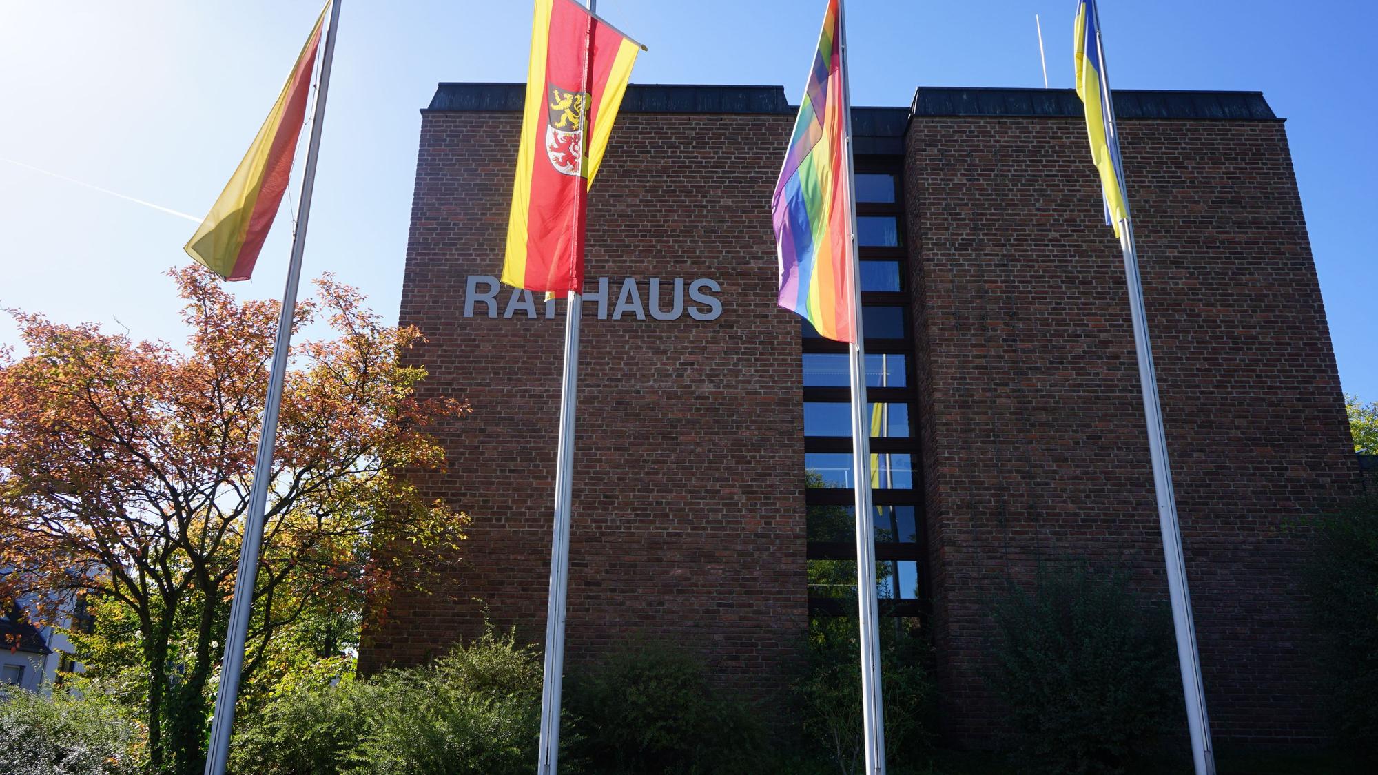 Vor dem Rathaus Kerpen, einem funktionalen Bau mit roten Ziegelsteinen, wehen Fahnen.