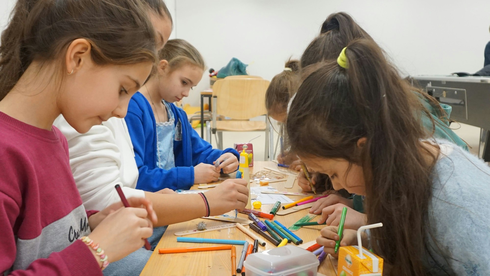 Kinder sitzen an einem Tisch und basteln.