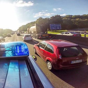 Ein Streifenwagen und andere Autos fahren auf der Autobahn.