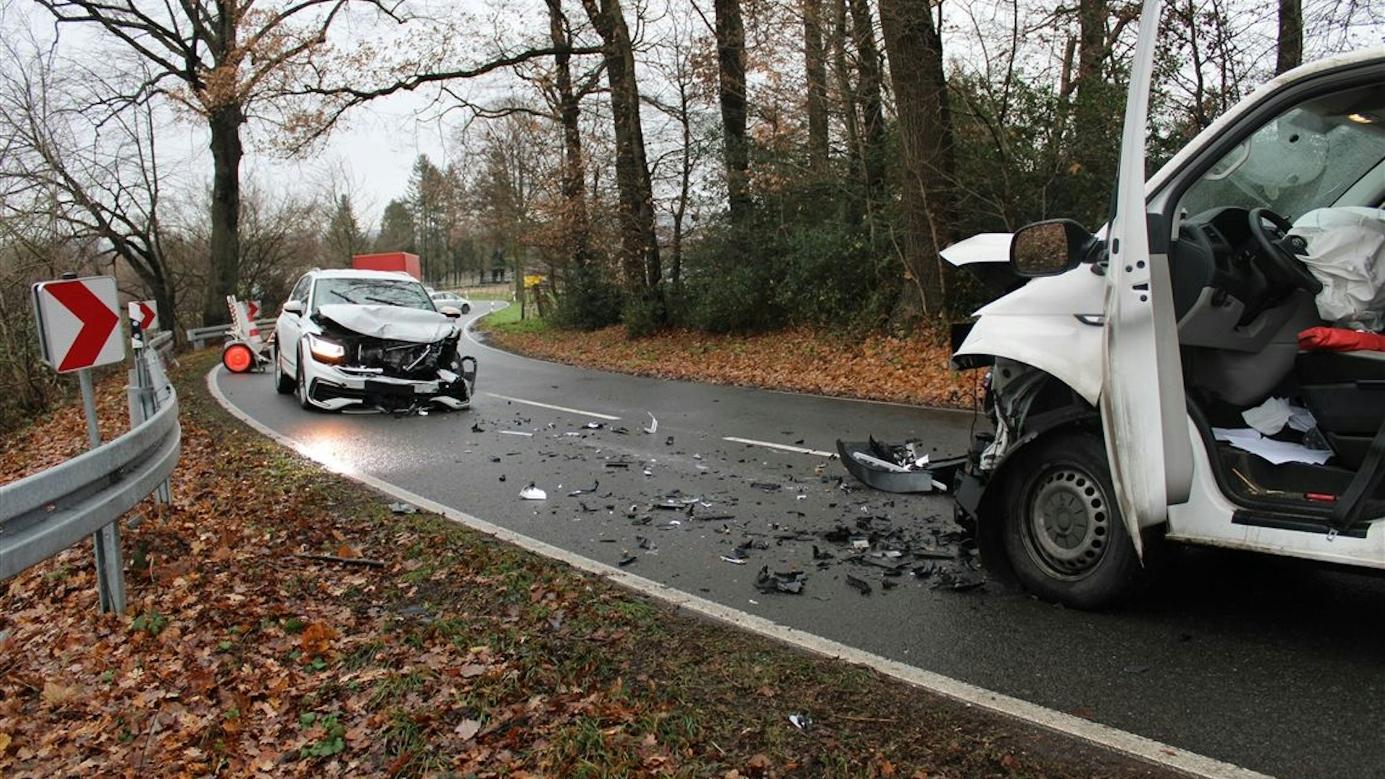 Zwei schwer beschädigte Autos stehen auf einer Straße, Splitter liegen auf dem Asphalt.