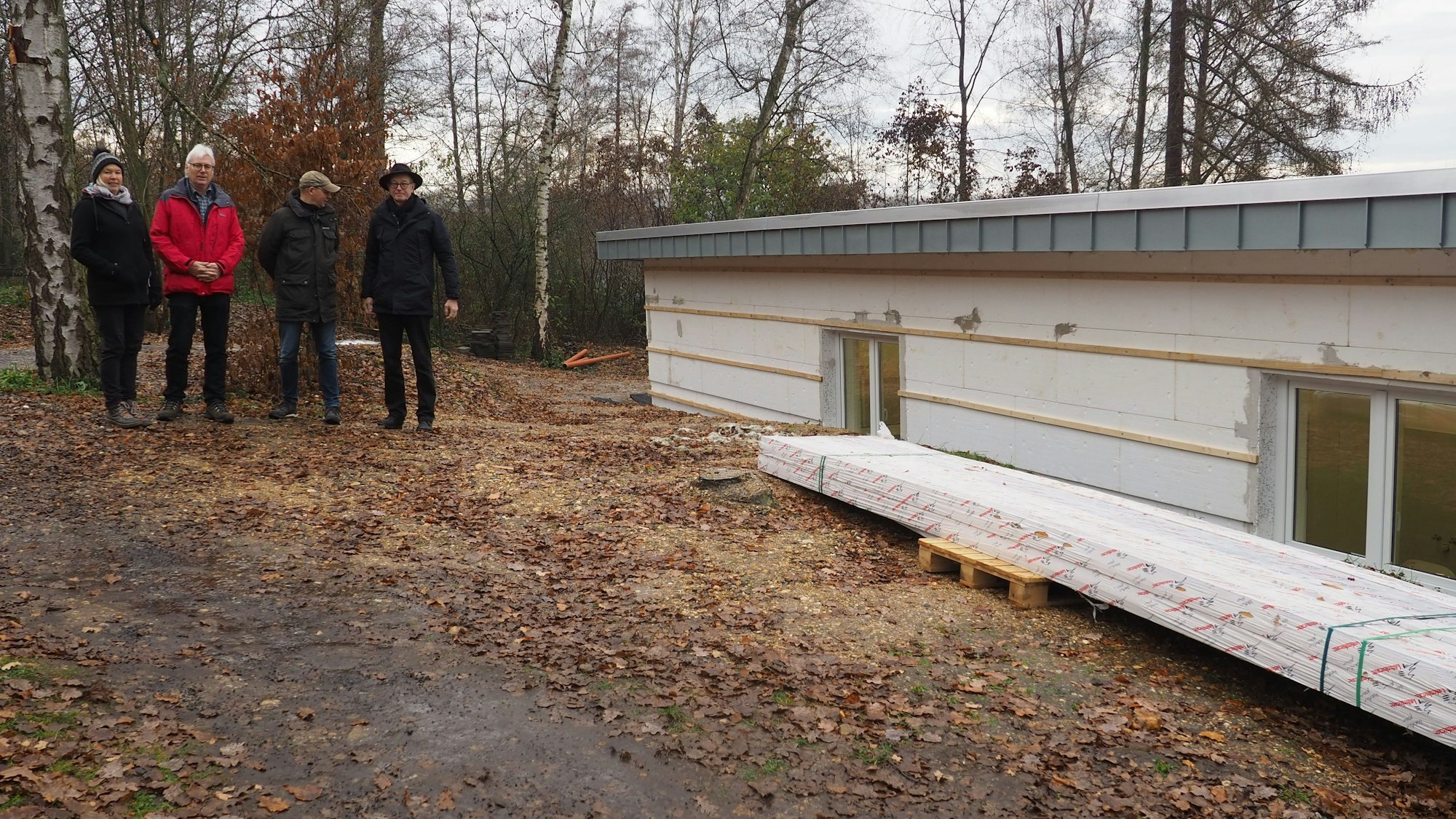 Silke Schäfer (v.l.), Jürgen Schreiber, Tobias Müller und Martin Schreiner stehen auf einem Waldweg. Neben ihnen ist ein Teil des Rohbaus des Vereinsheims.