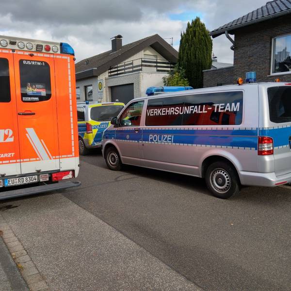 Ein Notarztwagen und Polizeiautos stehen vor einem Haus.