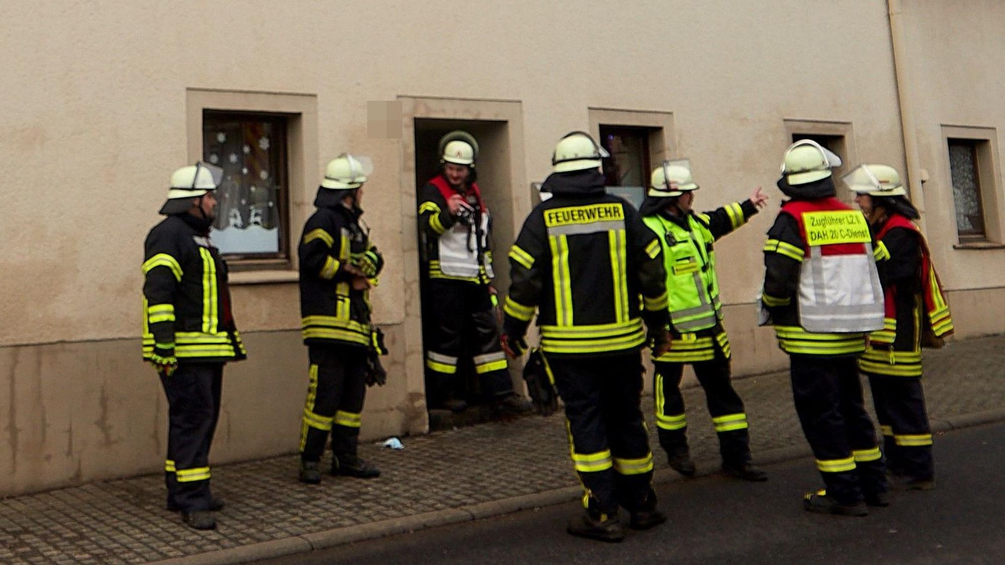 Feuerwehrleute stehen vor einem Haus in Dahlem.