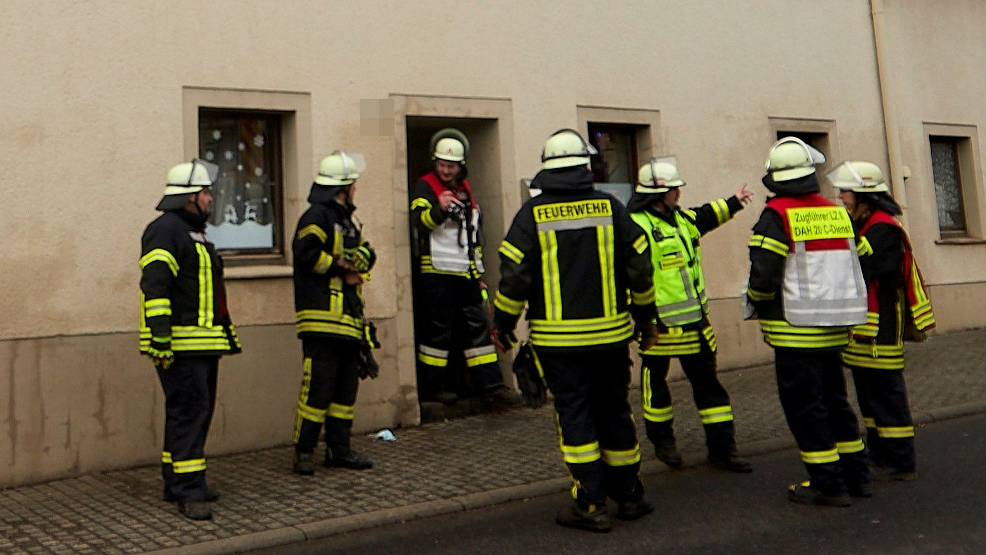 Feuerwehrleute stehen vor einem Haus in Dahlem.