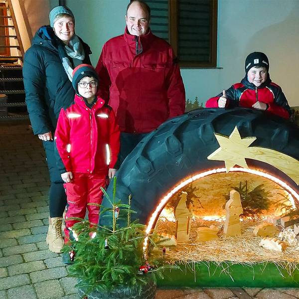 In einem Traktorreifen ist die Krippenszene integriert. Dahinter steht die Familie, die diese Krippe gebaut hat.
