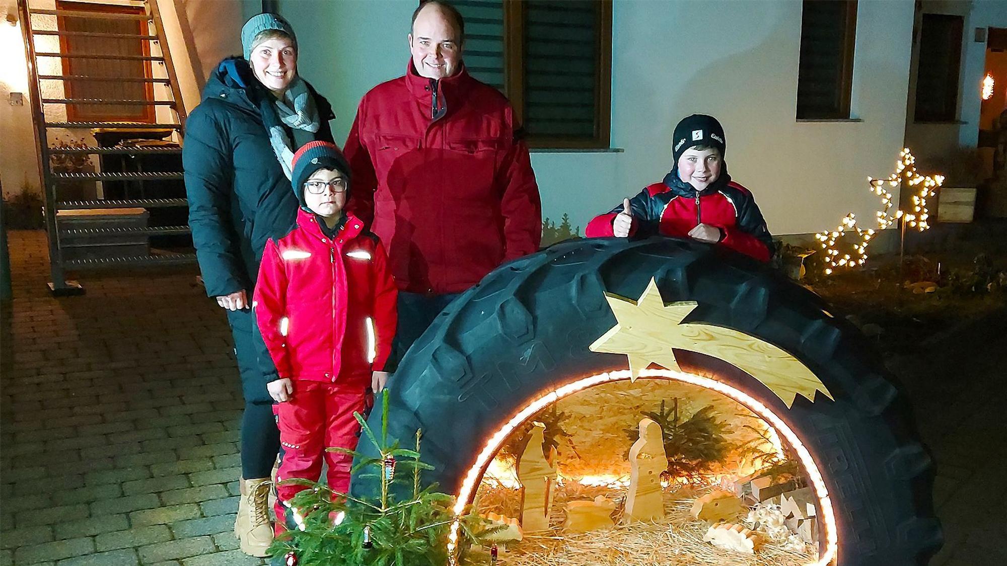 In einem Traktorreifen ist die Krippenszene integriert. Dahinter steht die Familie, die diese Krippe gebaut hat.