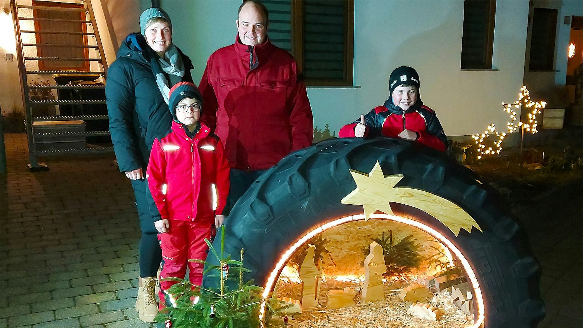 In einem Traktorreifen ist die Krippenszene integriert. Dahinter steht die Familie, die diese Krippe gebaut hat.