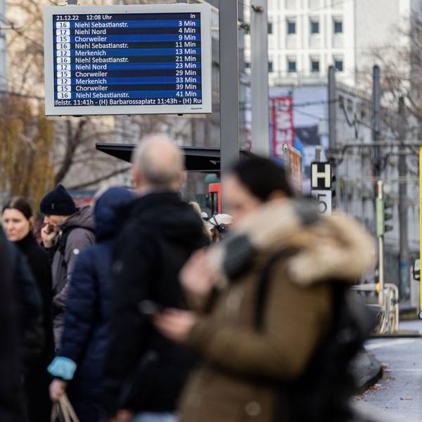 Bahnhaltestelle mit wartenden Menschen.