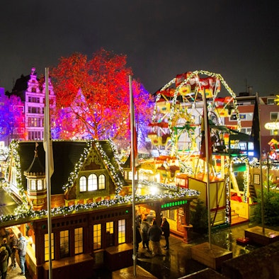 Hell erleuchtete Buden und ein Riesenrad für Kinder steht auf dem Alter Markt