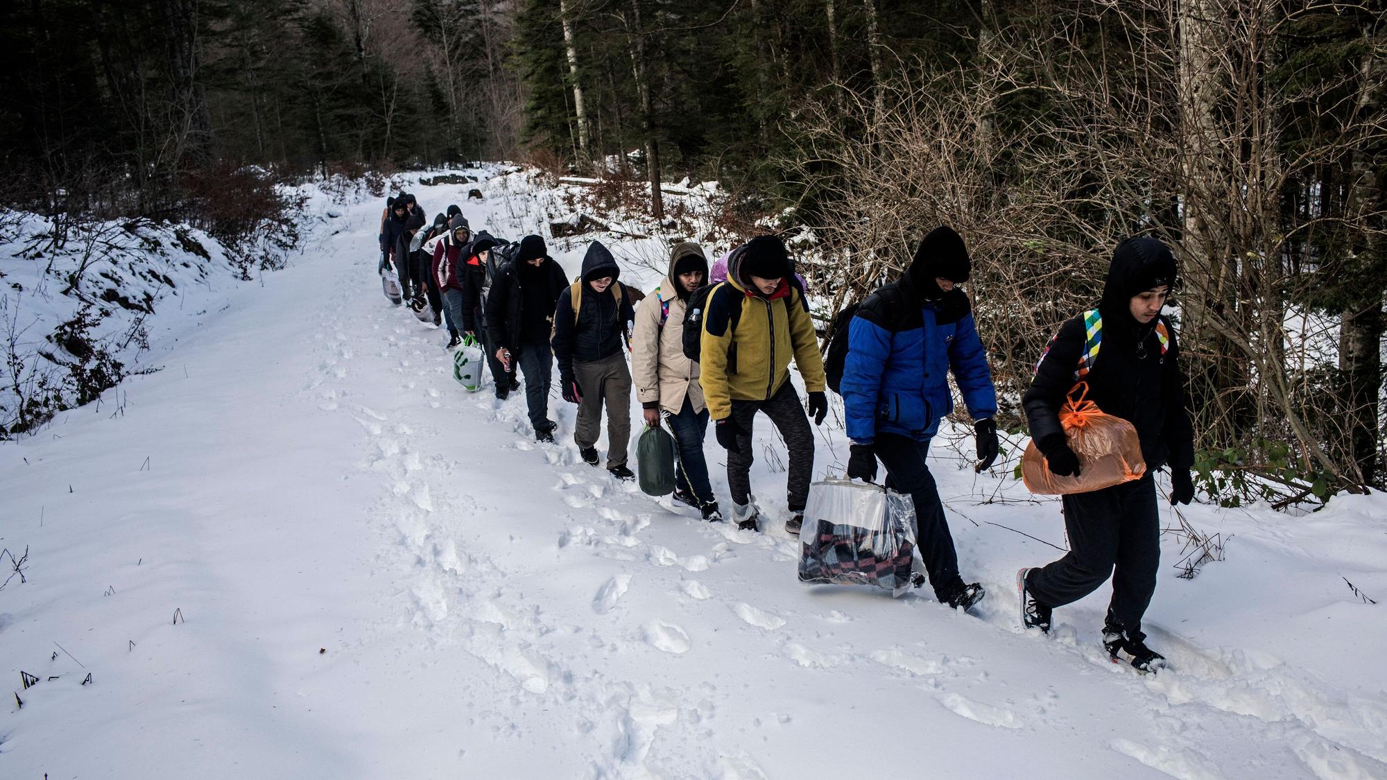Eine Gruppe ägyptischer Migranten geht im Schnee durch ein Berggebiet.