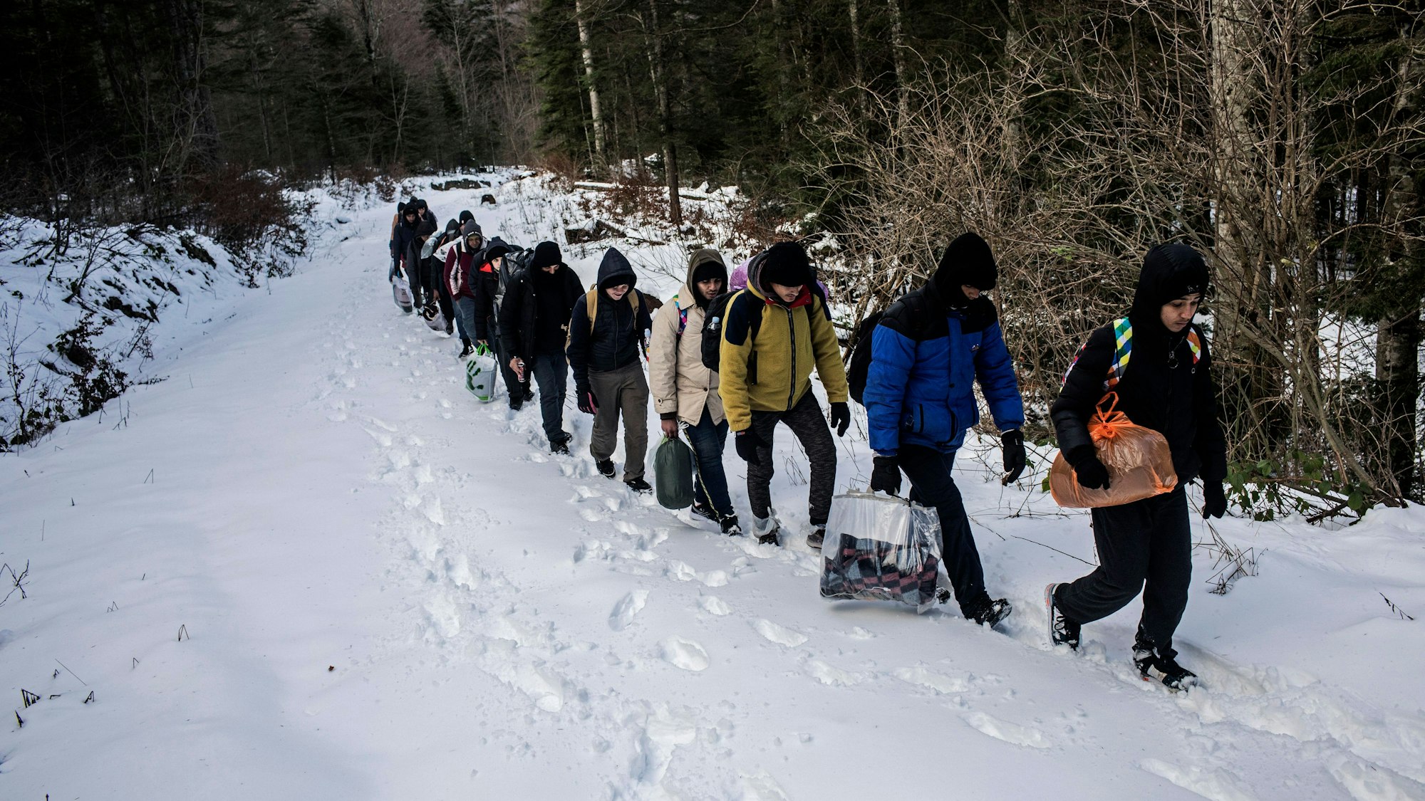 Eine Gruppe ägyptischer Migranten geht im Schnee durch ein Berggebiet.