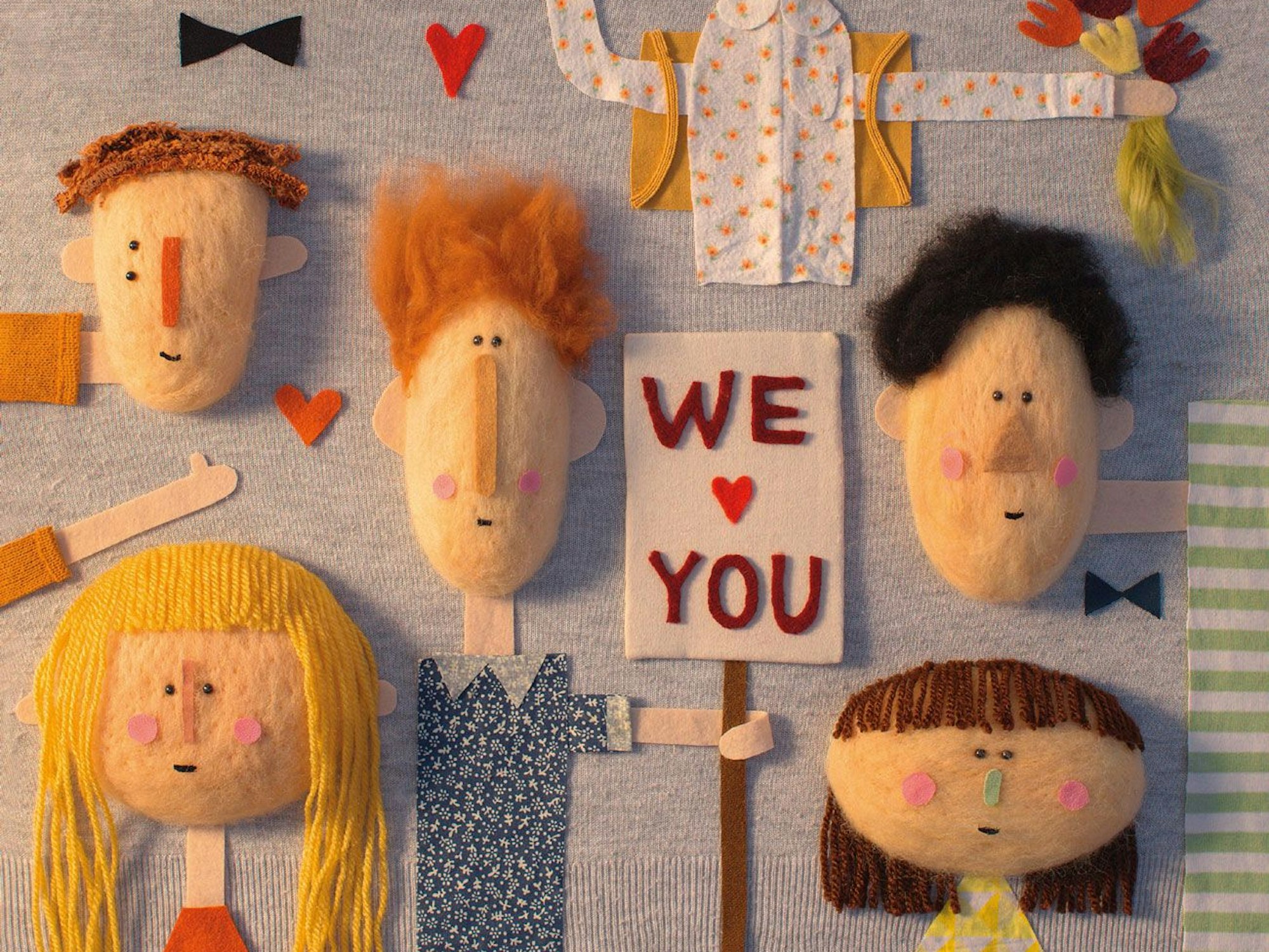 Kindergesichter und ein Schild mit der Aufschrift „We love You", Collage aus Stoff