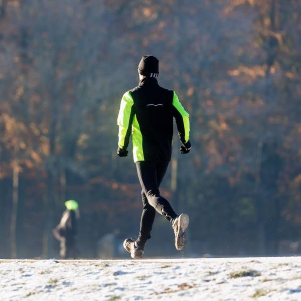 Ein Mann joggt durch den winterlichen Stadtpark.