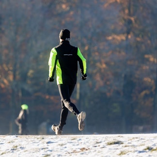 Ein Mann joggt durch den winterlichen Stadtpark.