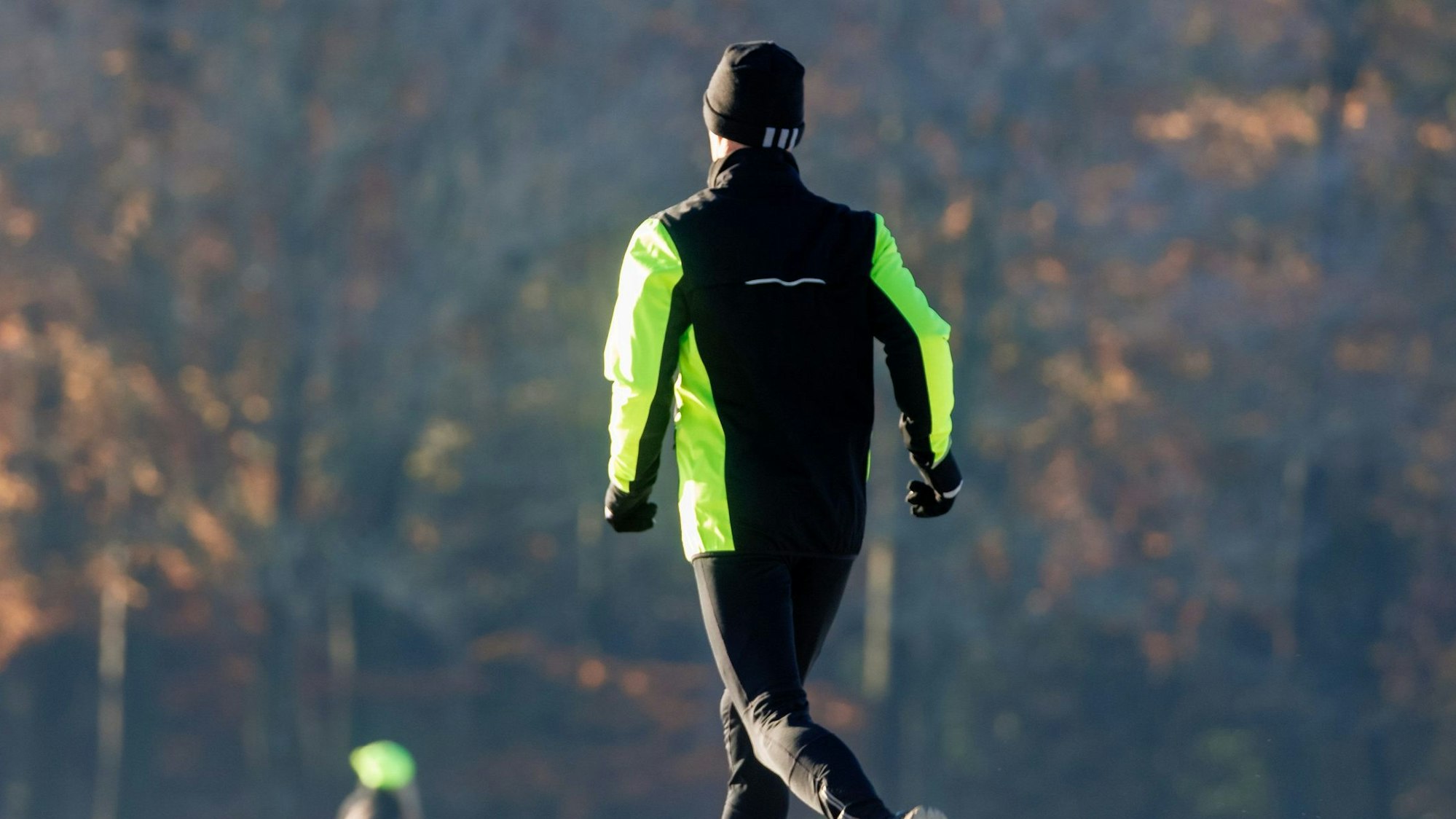Ein Mann joggt durch den winterlichen Stadtpark.
