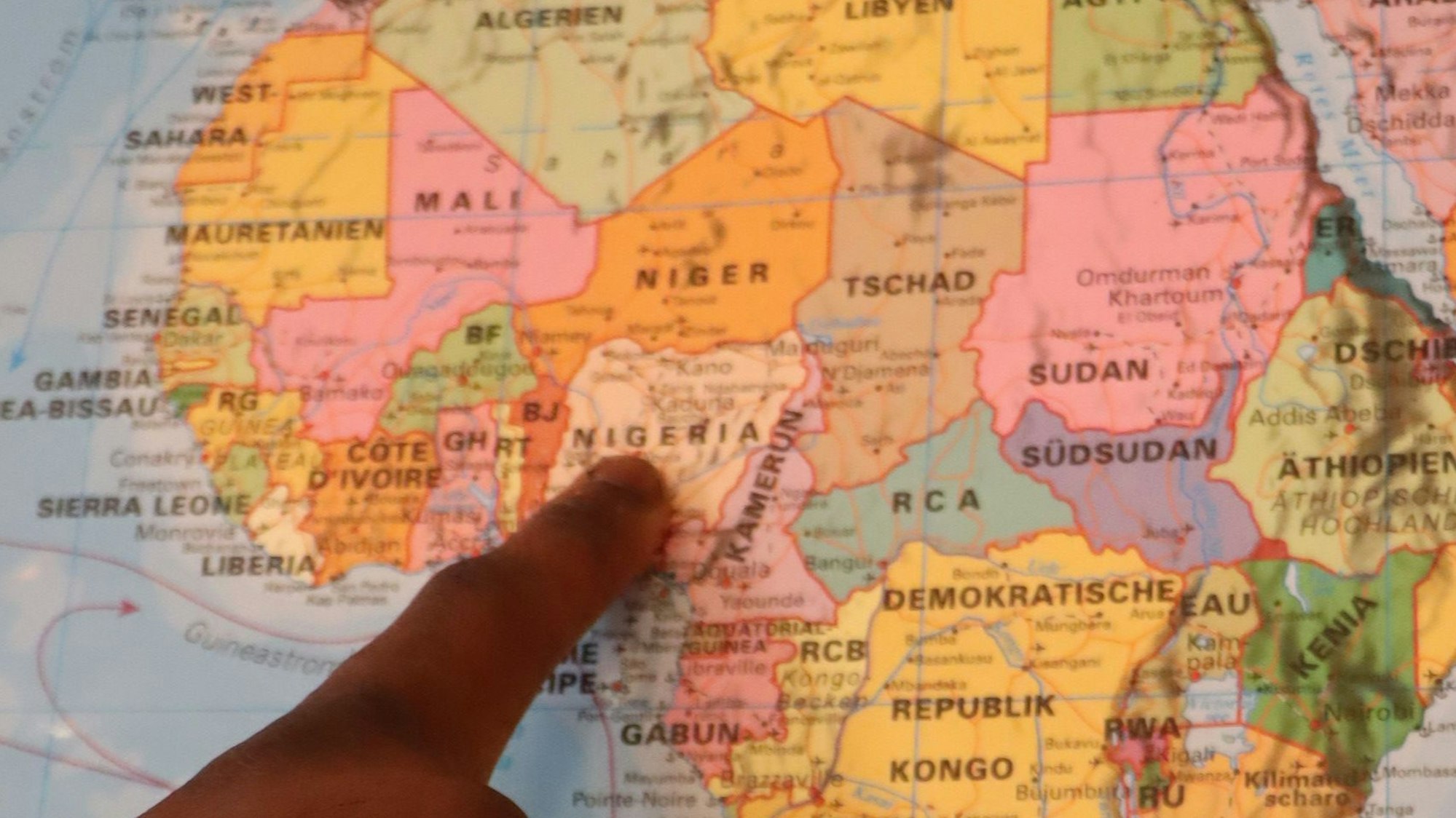 Mit dem Finger auf der Landkarte zeigt Michael Okwor Chinwoke auf seine Heimat Nigeria