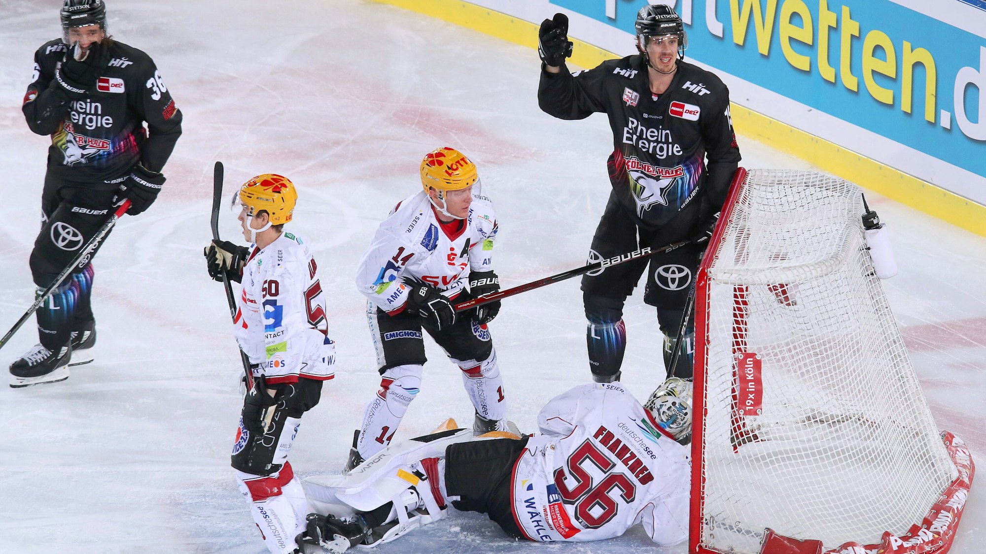 Köln, 22.12.2022, Eishockey, Penny DEL, 34. Spieltag, Cologne Stadium Series, RheinEnergieSTADION, Kölner Haie - Fischtown Pinguins Bremerhaven: Kölns Andreas Thuresson und Louis-Marc Aubry schießen den Puck auf das Tor von Maximilian Franzreb, Torhüter von Fischtown Pinguins Bremerhaven. Das Tor steht queer auf dem Eis.