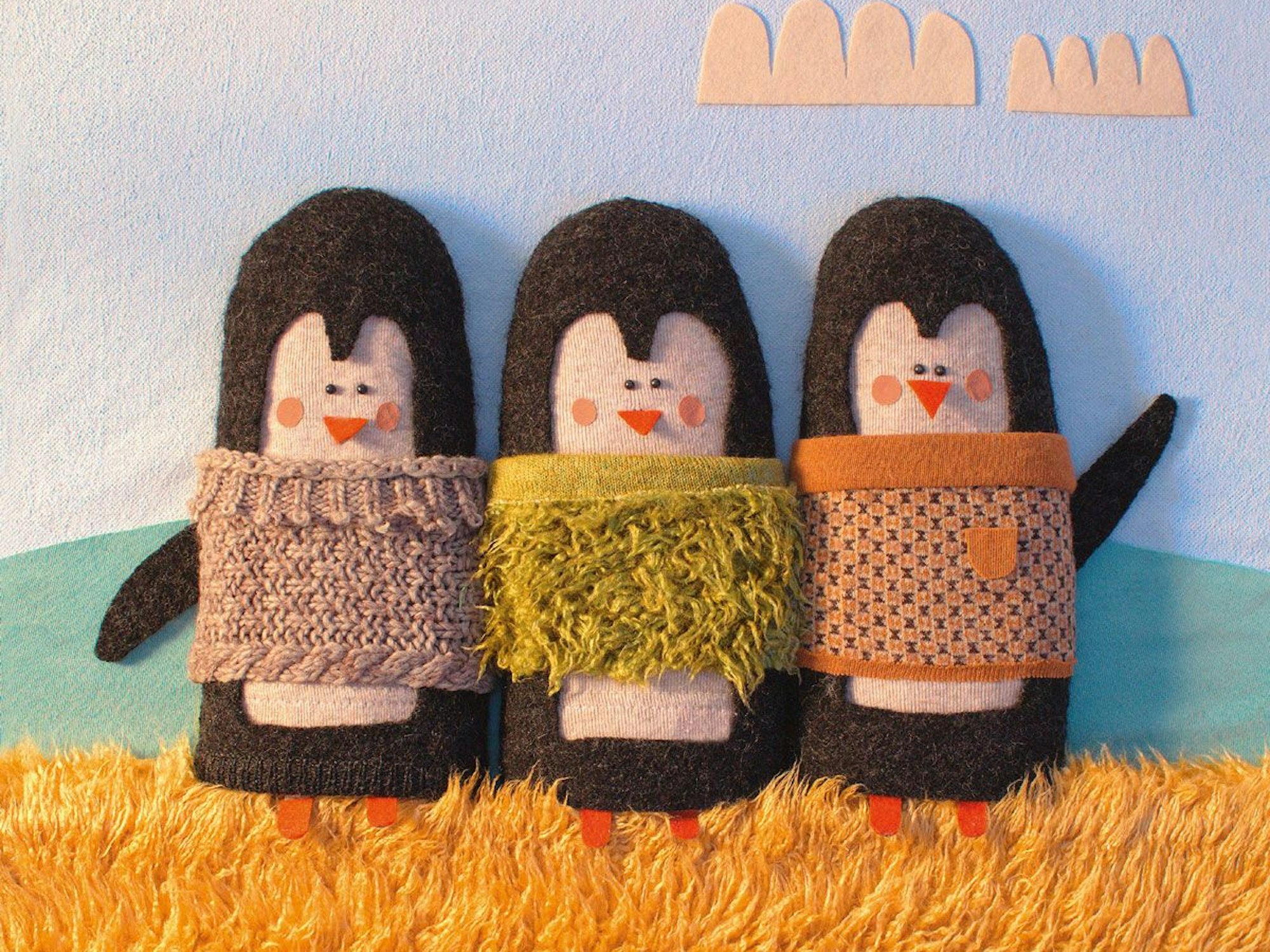 Drei Pinguine mit Wollpullover, Collage aus Stoff