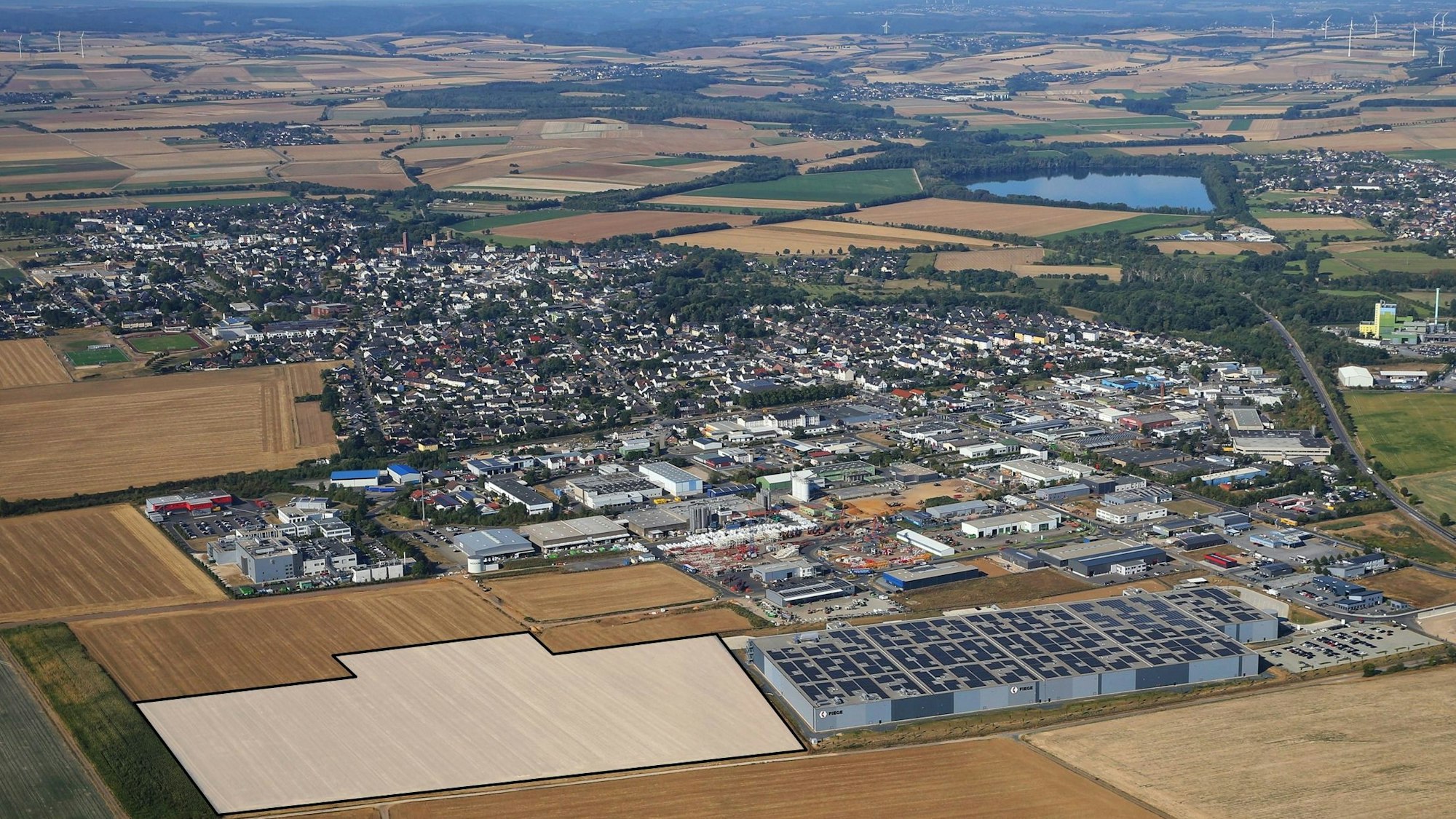 Drohnenansicht des Gewerbegebiets der Stadt Zülpich mit vielen Fabrikhallen und Feldern.