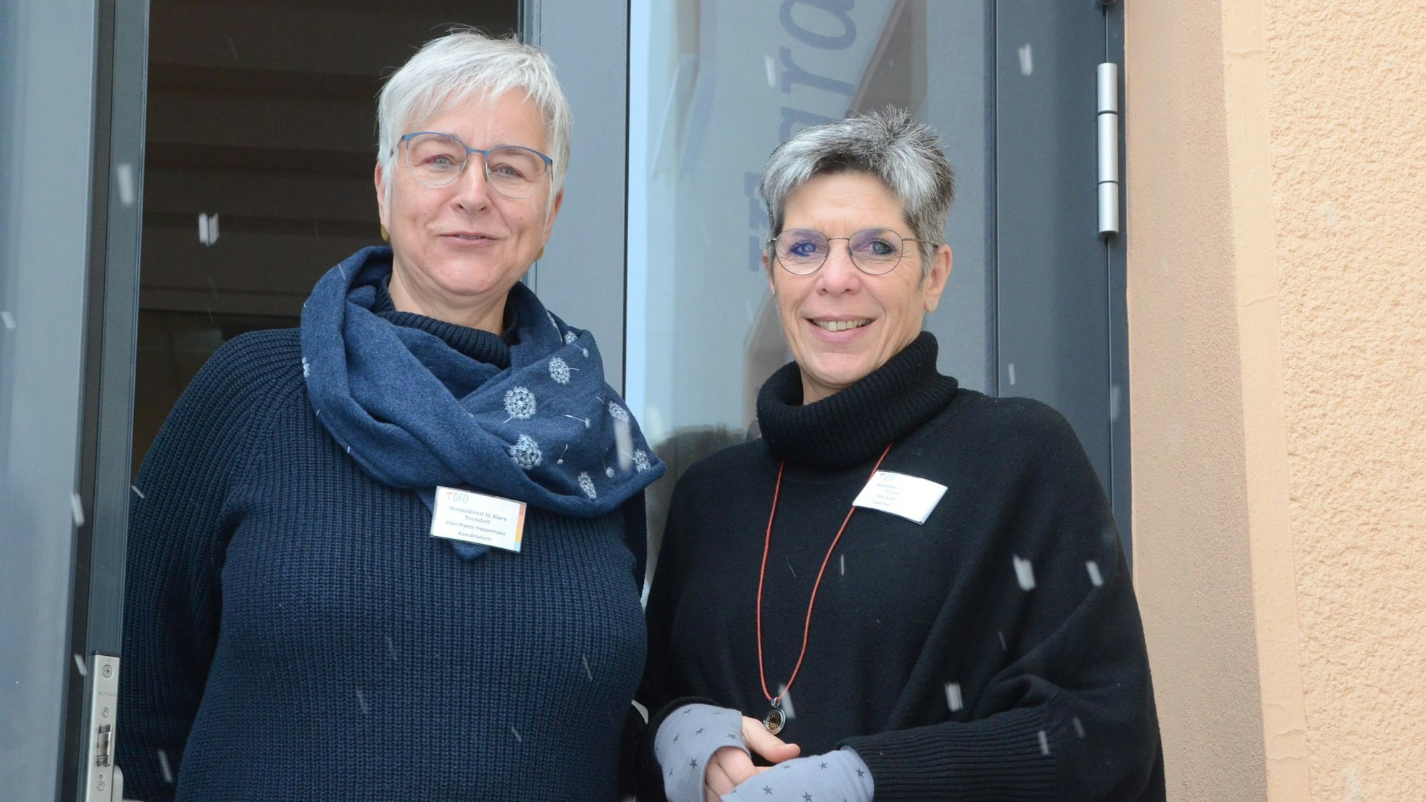 Ellen Preetz-Heppelmann und Hilla Schlimbach stehen in einem Hauseingang, Schneeflocken fallen vor der Linse der Kamera.