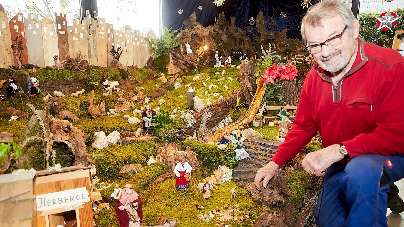 Ein Mann kniet vor einer großen Weihnachtskrippe.