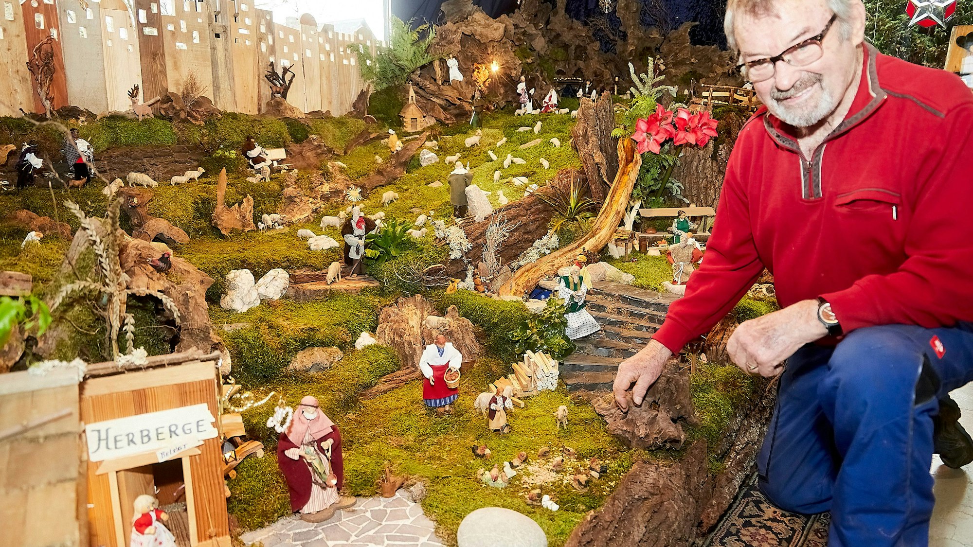 Ein Mann kniet vor einer großen Weihnachtskrippe.