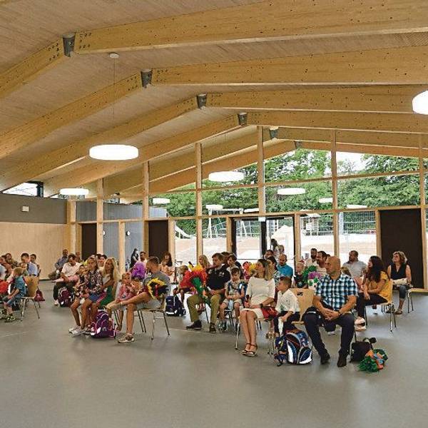 In einem großen Raum in der neu gebauten Grundschule in Neschen sitzen viele Menschen.