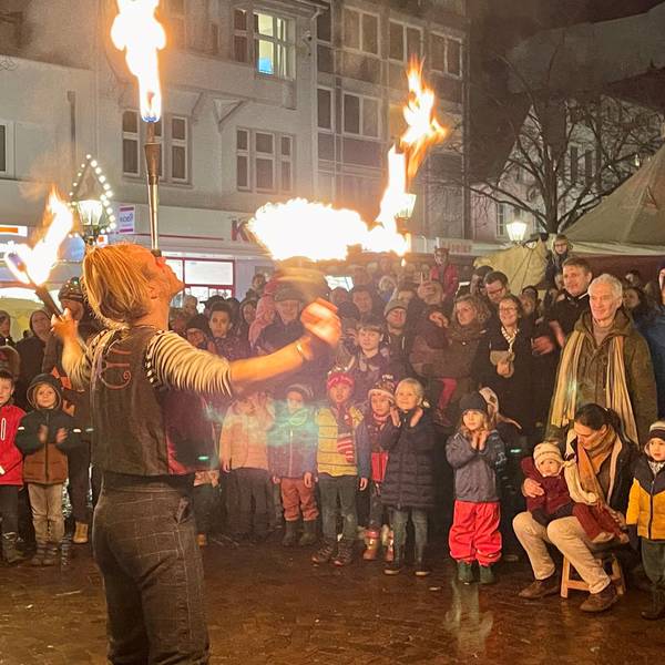 Ein Feuerkünstler wird von Kindern und Erwachsenen bestaunt.