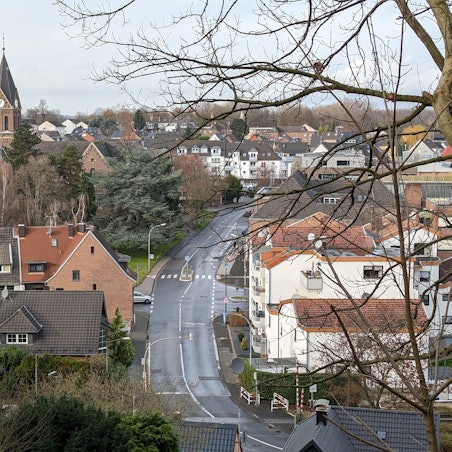 Ansicht von Alt-Hürth mit Straße und Kirche, bewölkt.