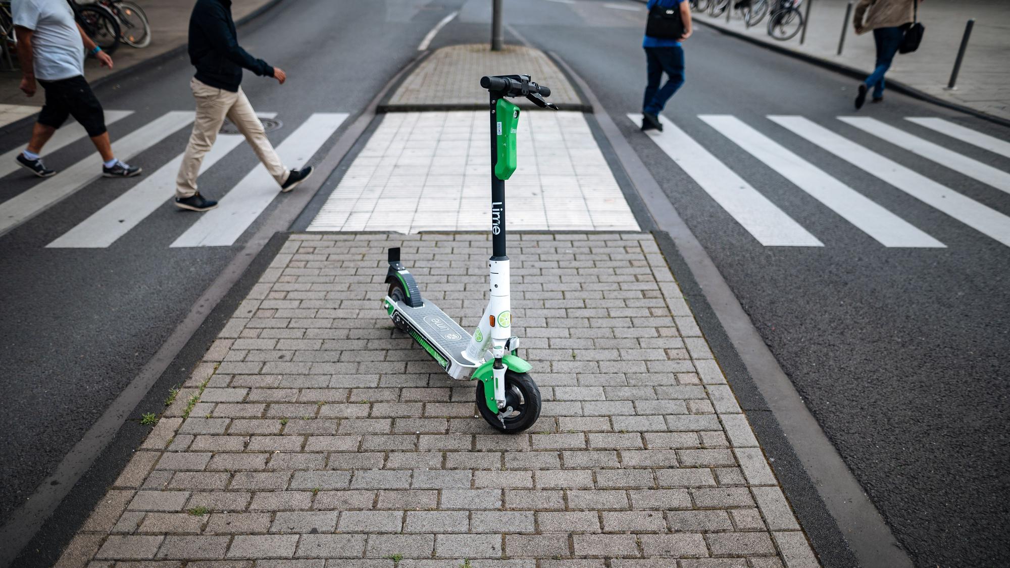 Ein E-Scooter des Unternehmens Lime steht vor einem Zebrastreifen in der Kölner Innenstadt.