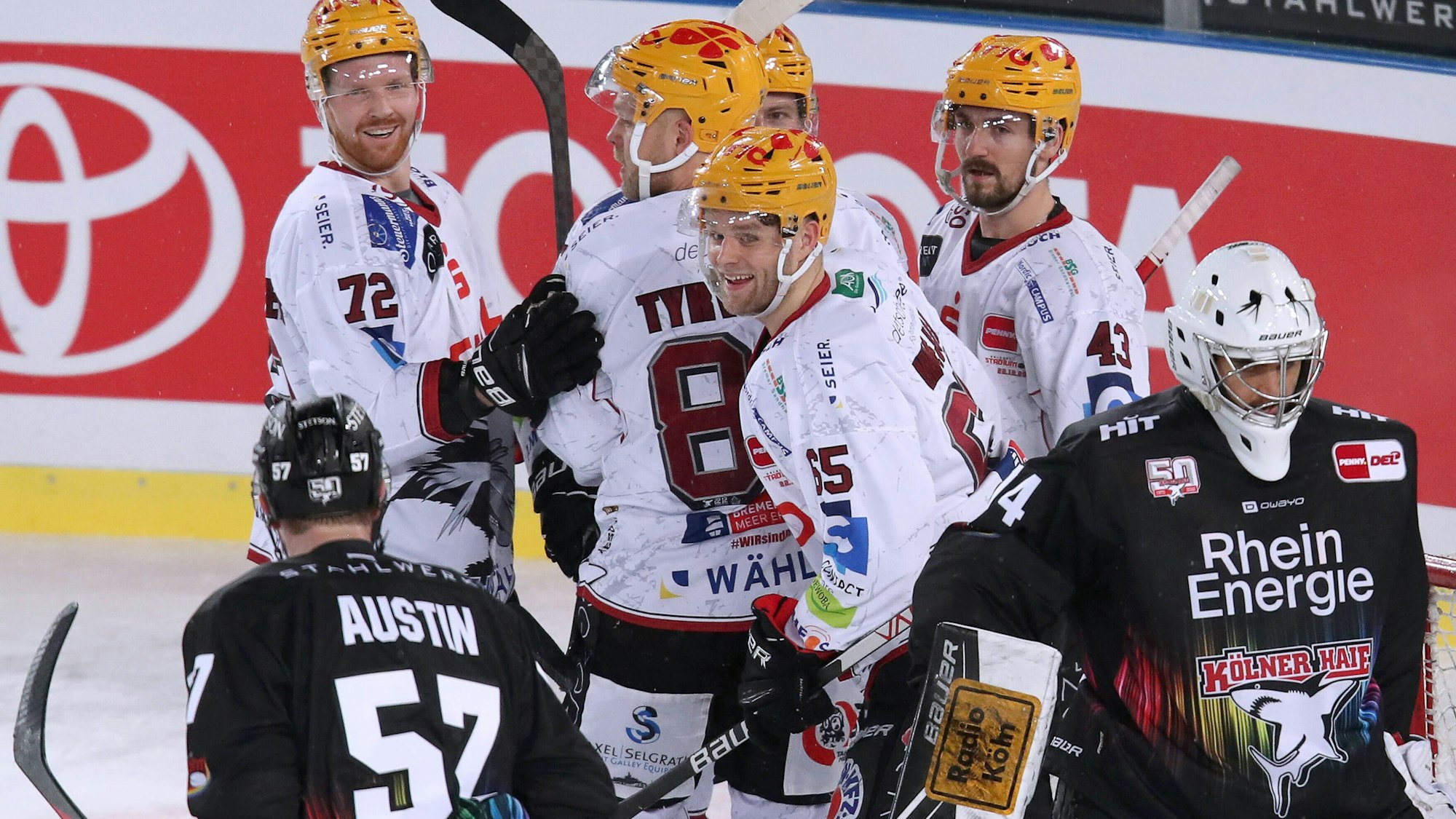 Spieler der Kölner Haie lassen die Köpfe hängen, Bremerhavener Spieler jubeln.