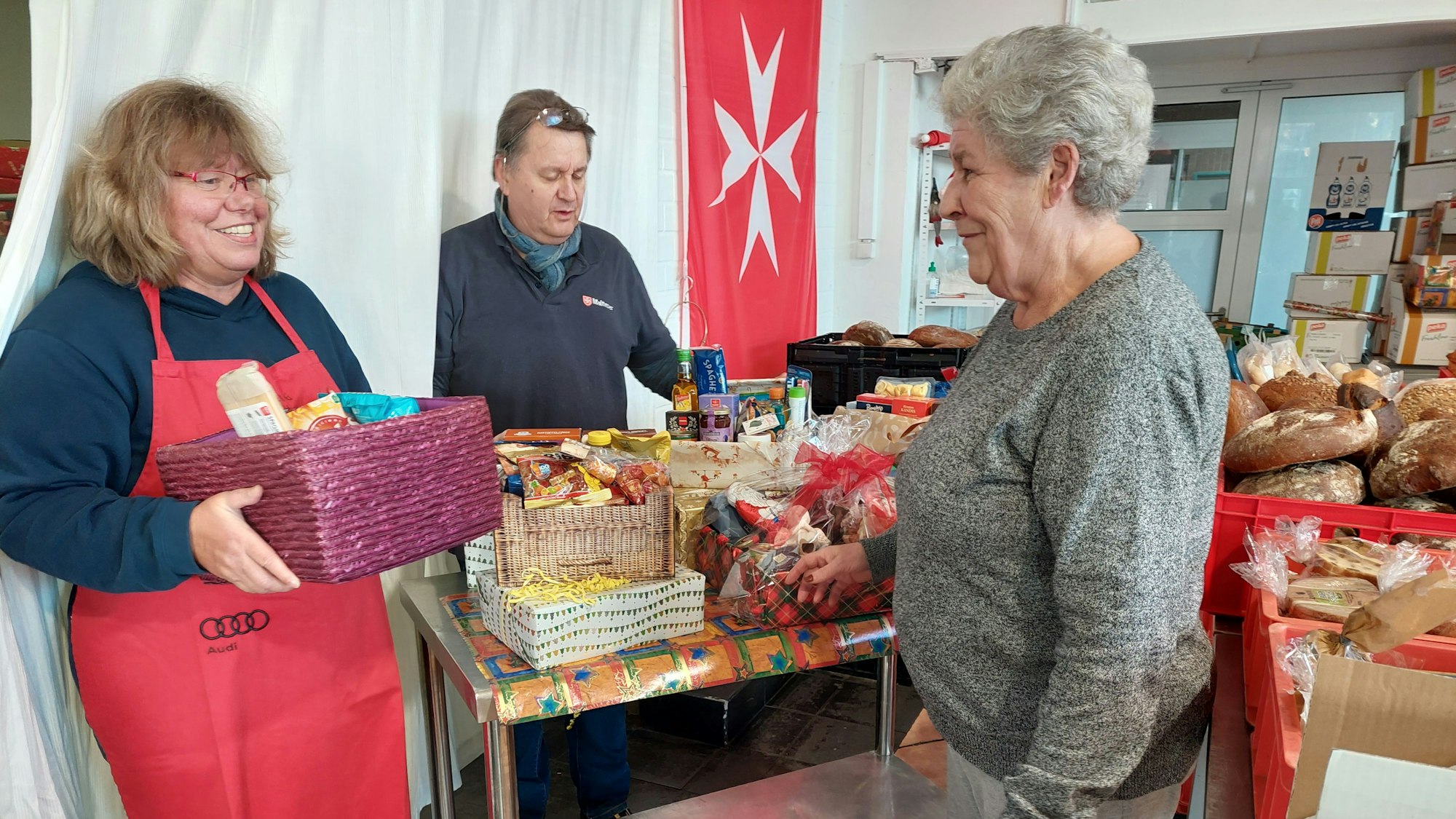 Malteser Tafel: Das Bild zeigt Petra Drehert und Gerhard Kunst, die die Tafel an der Steinstraße 6 leiten, mit einer Kundin.
