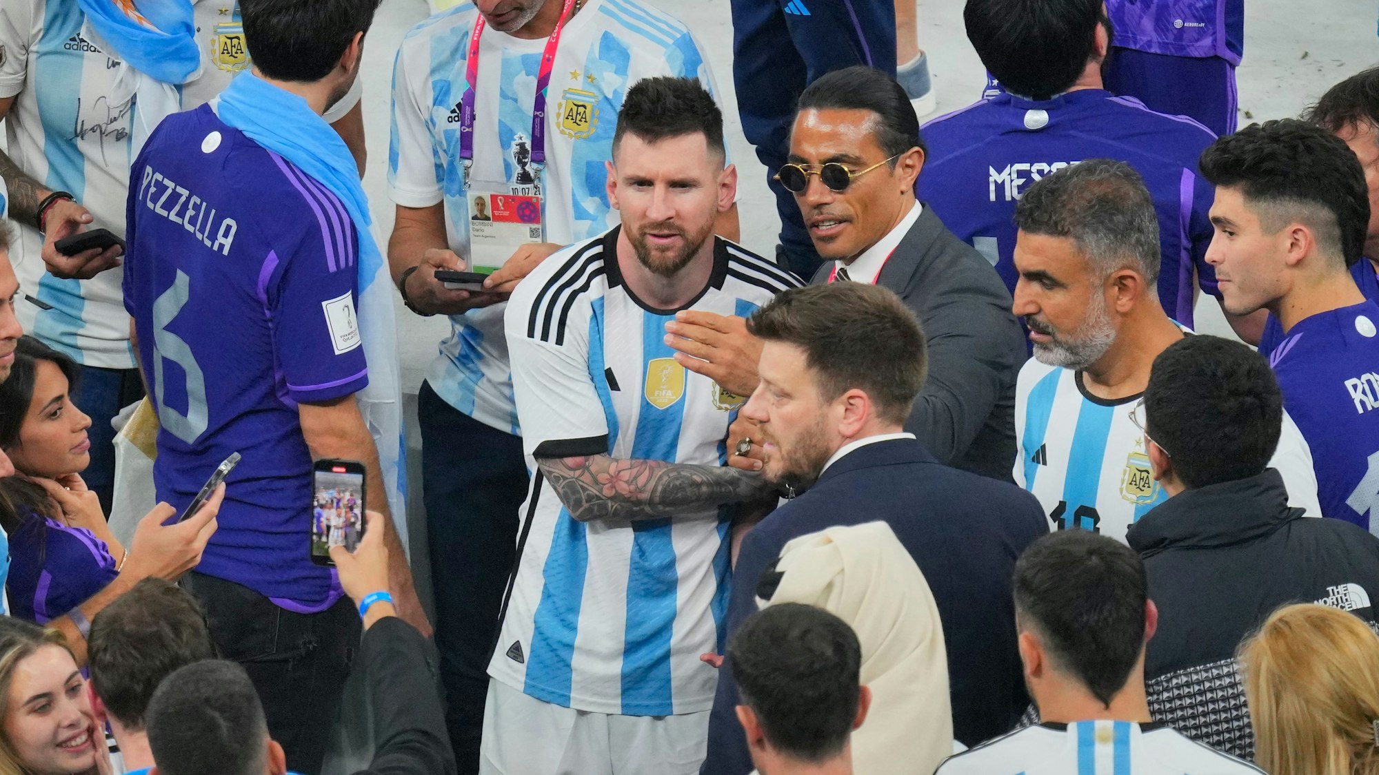 Ein Mann macht mit seinem Handy ein Foto von Nusret Gokce (Mitte rechts), auch bekannt als Koch oder Salt Bae, mit dem argentinischen Nationalspieler Lionel Messi am Ende des WM-Endspiels