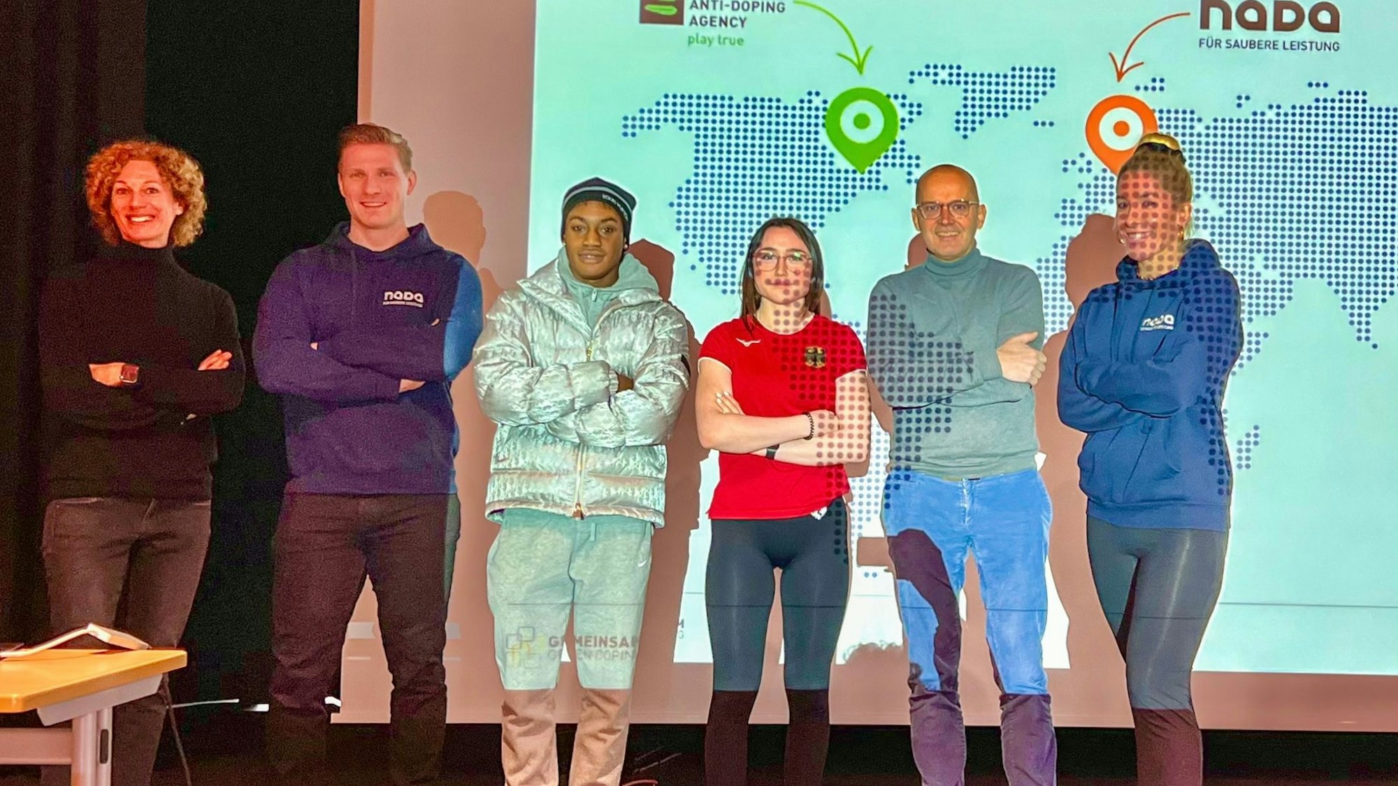 Sechs Personen stehen vor einer Powerpointfolie der NADA auf einer Bühne.