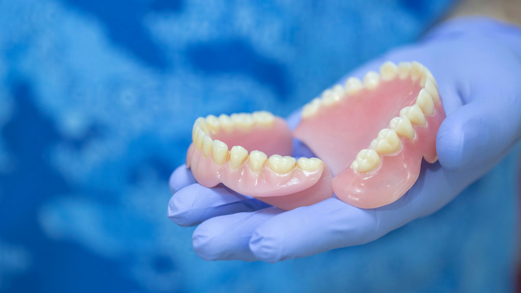 Eine Person hält ein Gebiss in der Hand und präsentiert es.