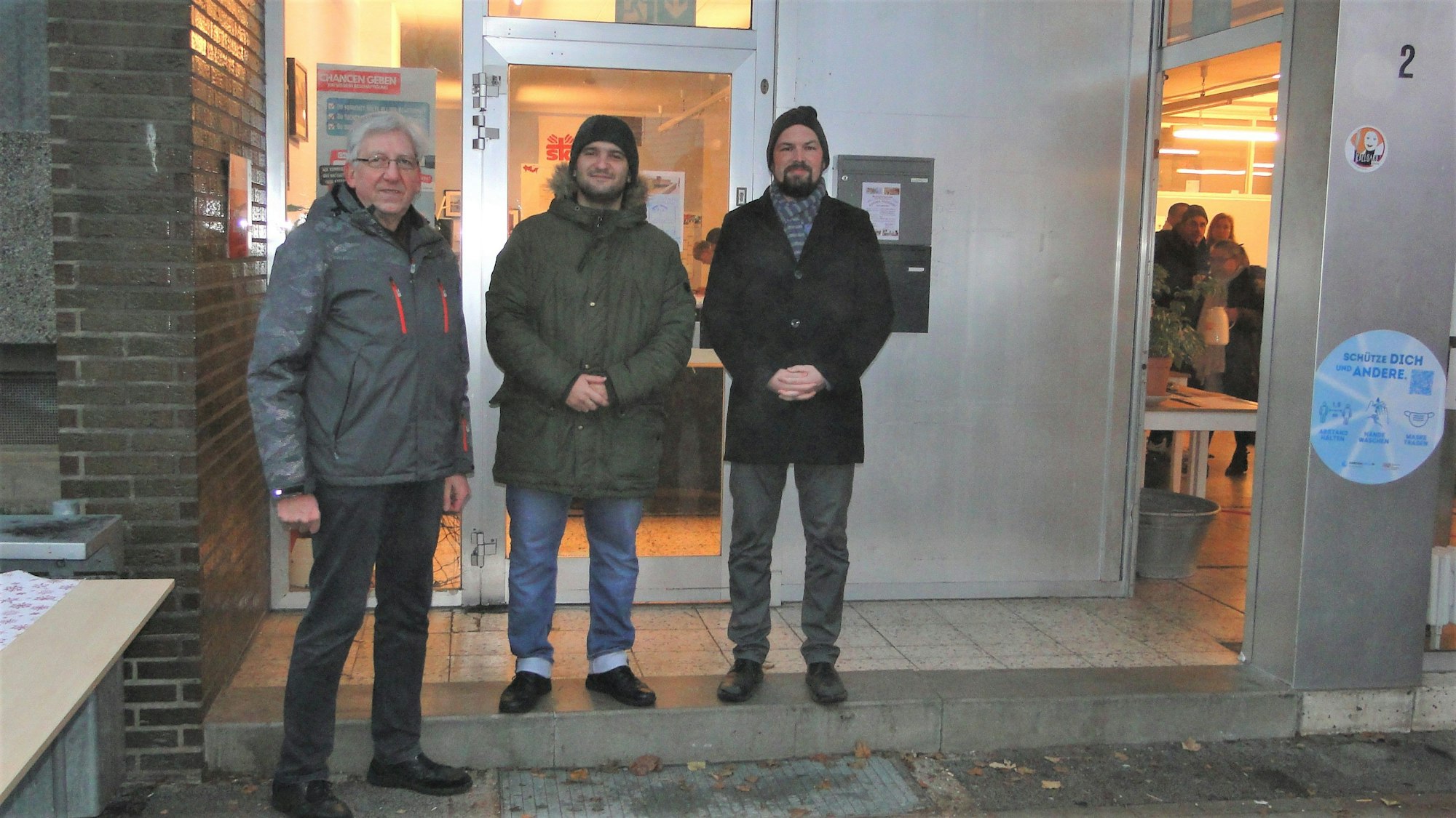 Die Drei stehen vor einem Gebäudeeingang.