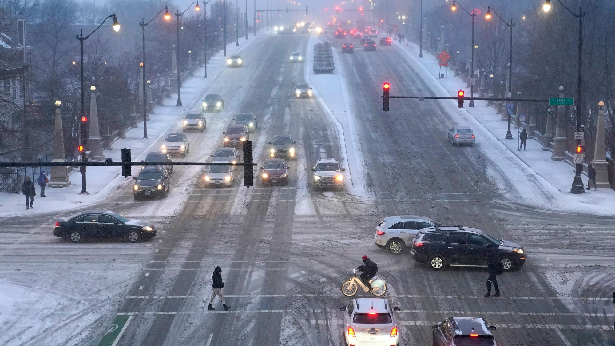 Fußgänger gehen über glatte Straßen. Ein arktisches Sturmtief bringt über die Weihnachtstage drastische Temperaturstürze und extreme Kälte in die USA.