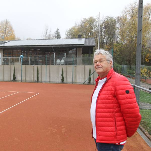 Zwei Männer in blauer und roter Jacke stehen auf einem Tennisfeld.