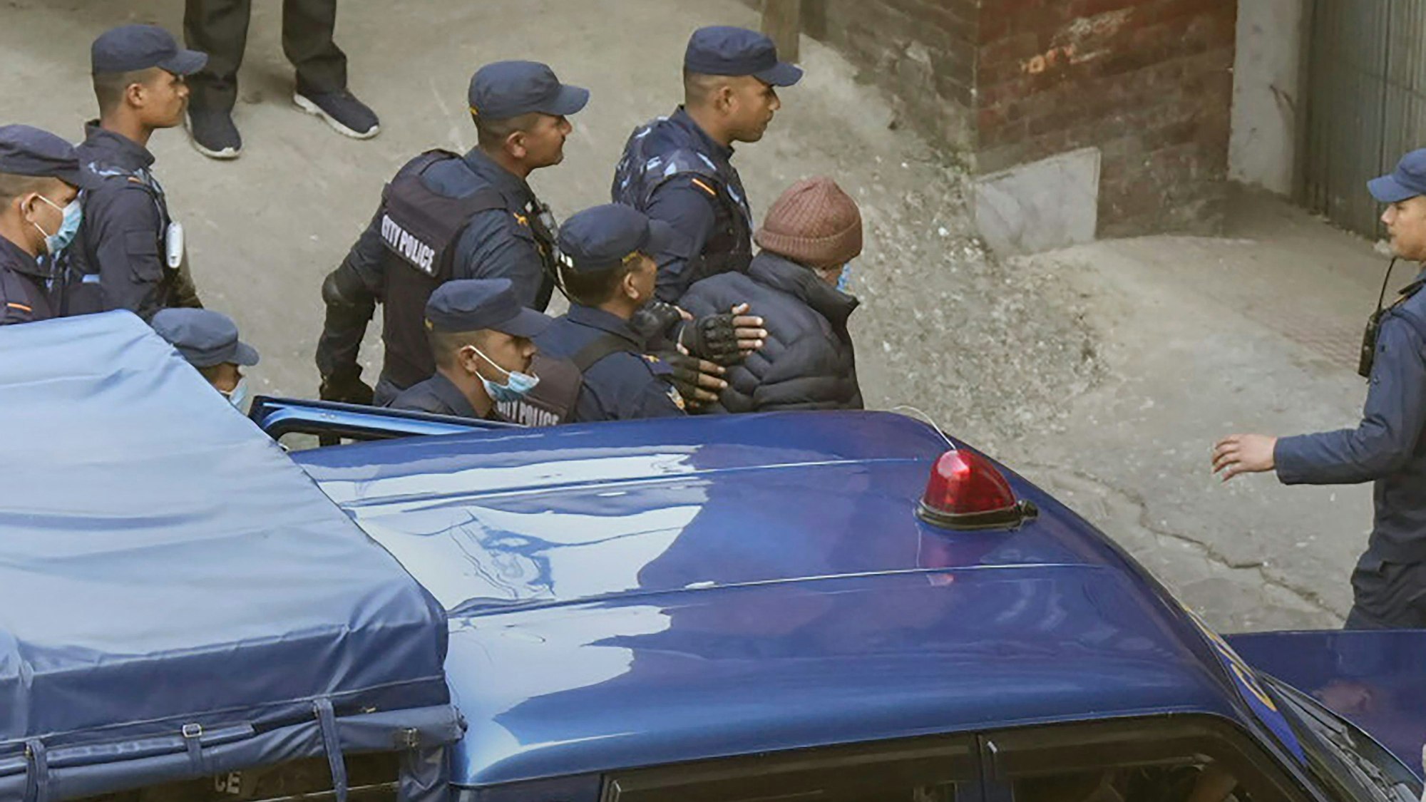 Nepalesische Polizisten eskortieren Charles Sobhraj (mit brauner Mütze) zur Migrationsbehörde in Kathmandu. Der französische Serienmörder ist nach 19 Jahren Haft aus dem nepalesischen Gefängnis entlassen worden.