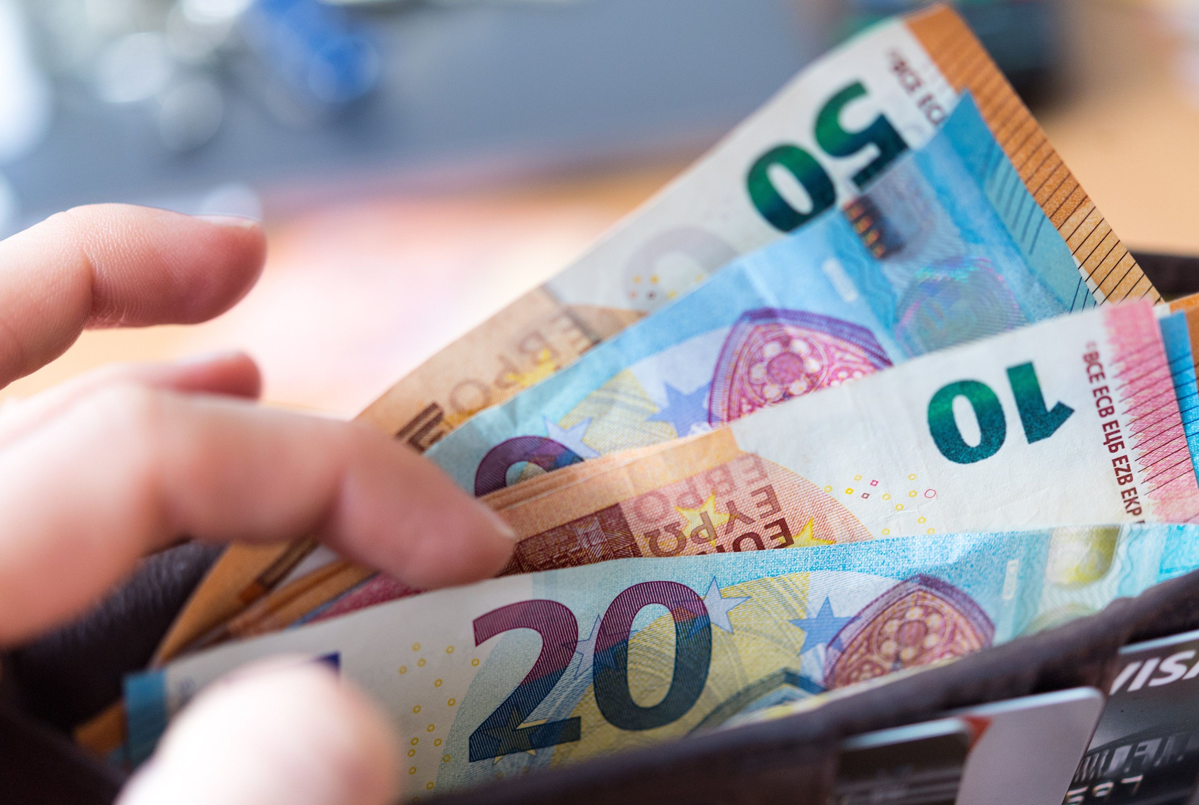 Eine Frau hält eine Geldbörse mit Banknoten in der Hand.