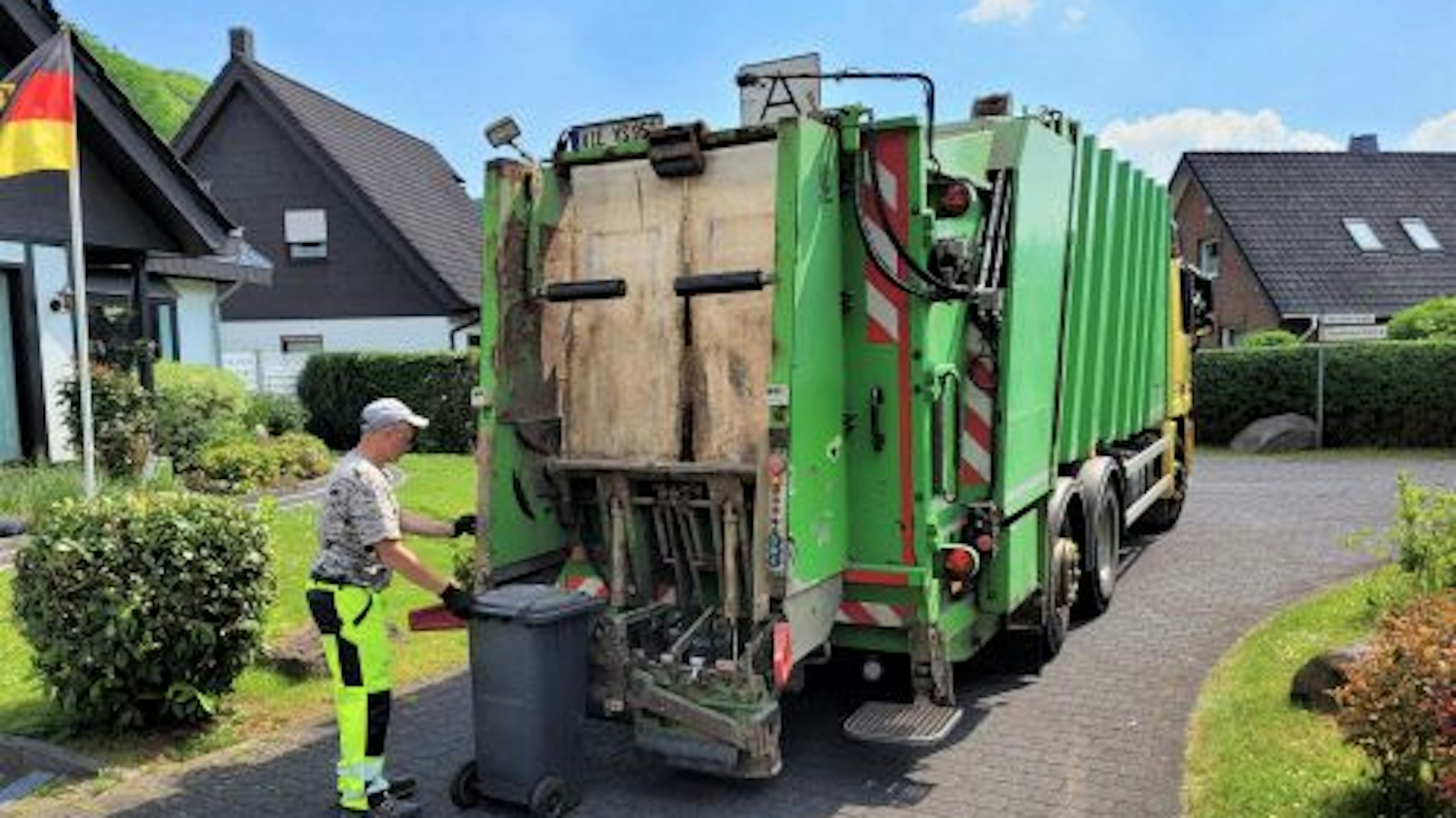 Ein Müllmann leert die Restmülltonne am Müllwagen.