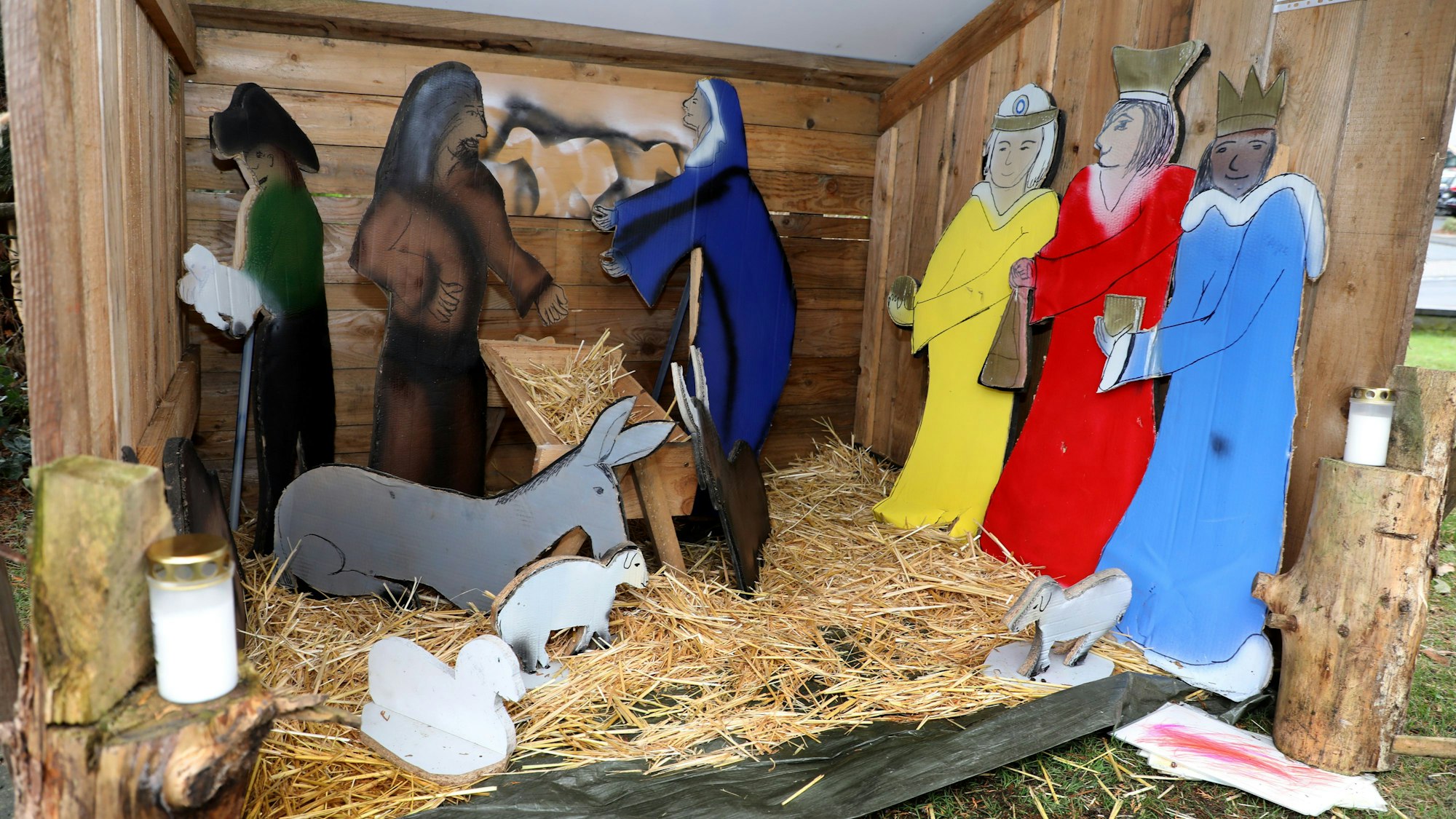 Bunte Krippenfiguren stehen auf Stroh.