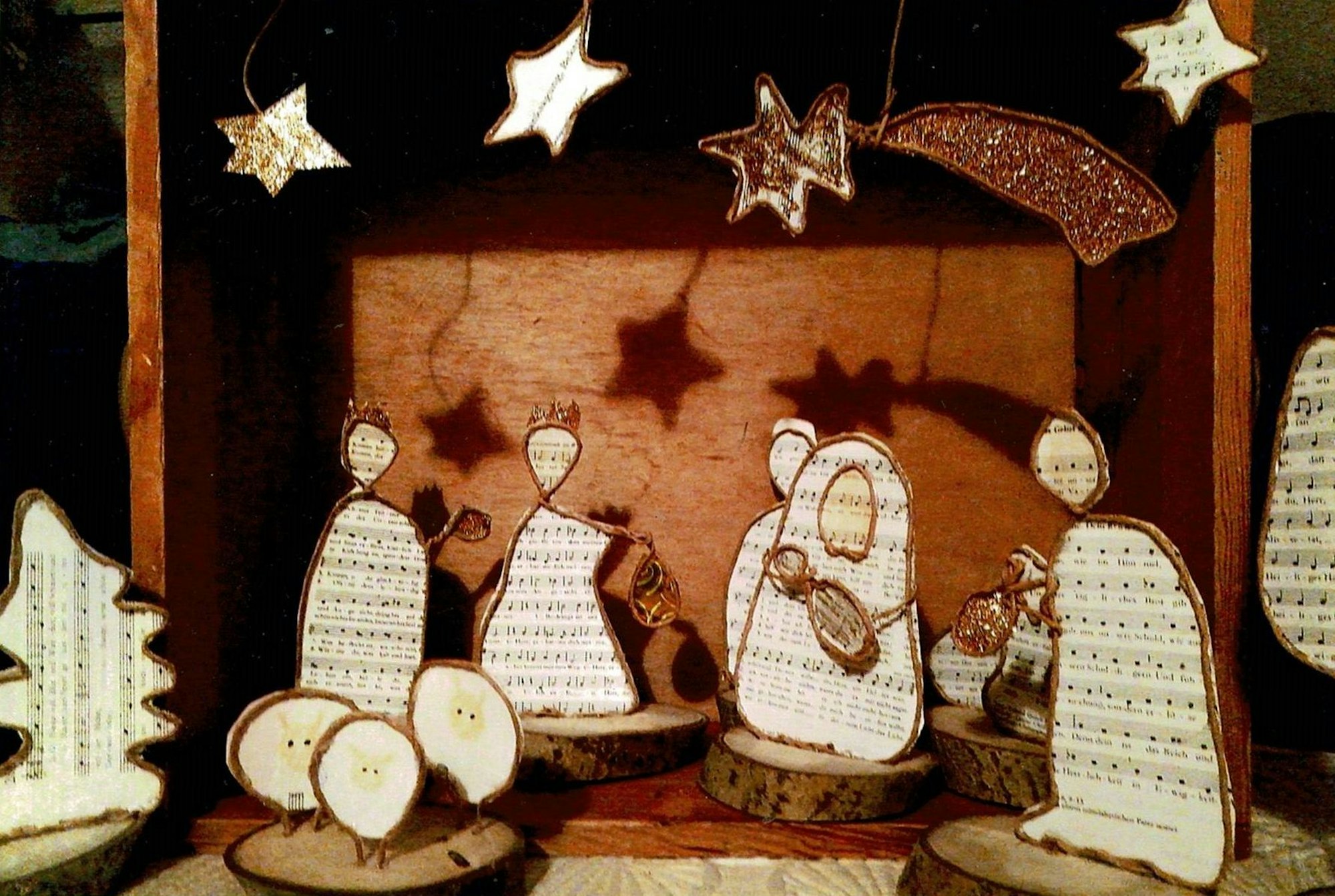 Krippenfiguren aus Notenpapier stehen auf Holzscheiben.