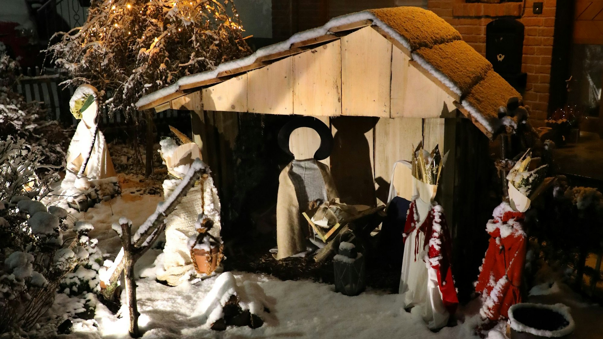 Krippenfiguren stehen auf einer Schneelandschaft.