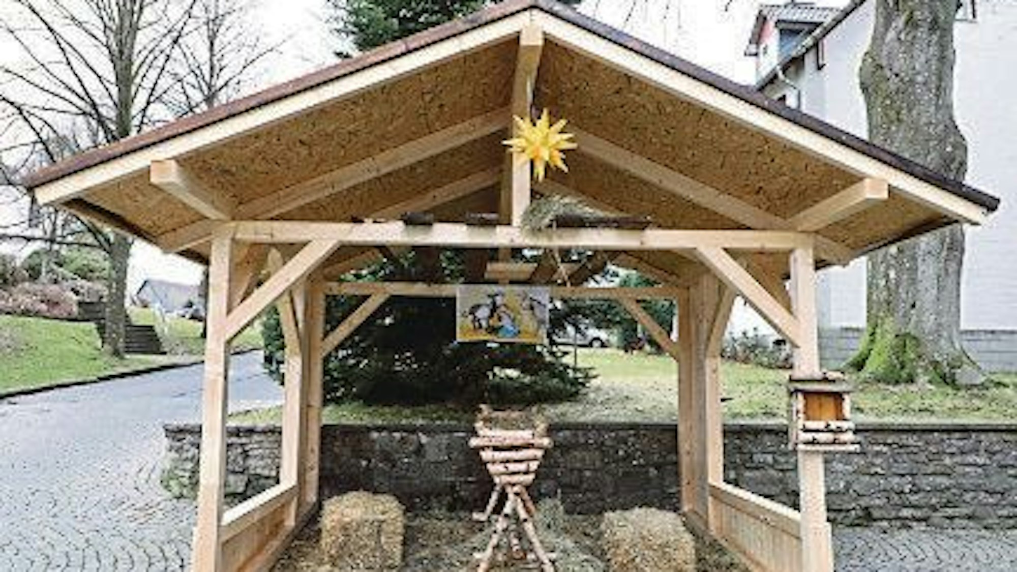Eine Holzhütte überdacht eine Holzwiege und Stroh.