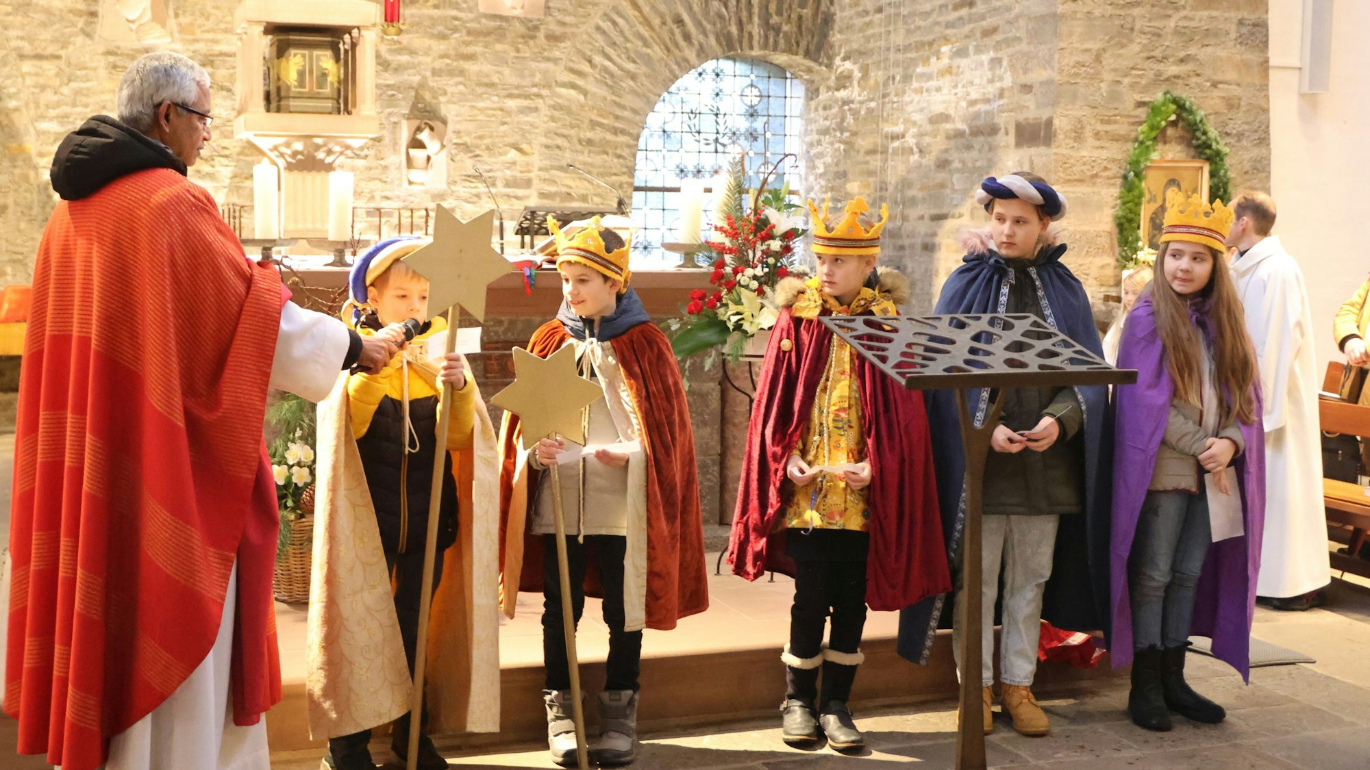 Einige Sternsinger und der Pater in der Kirche